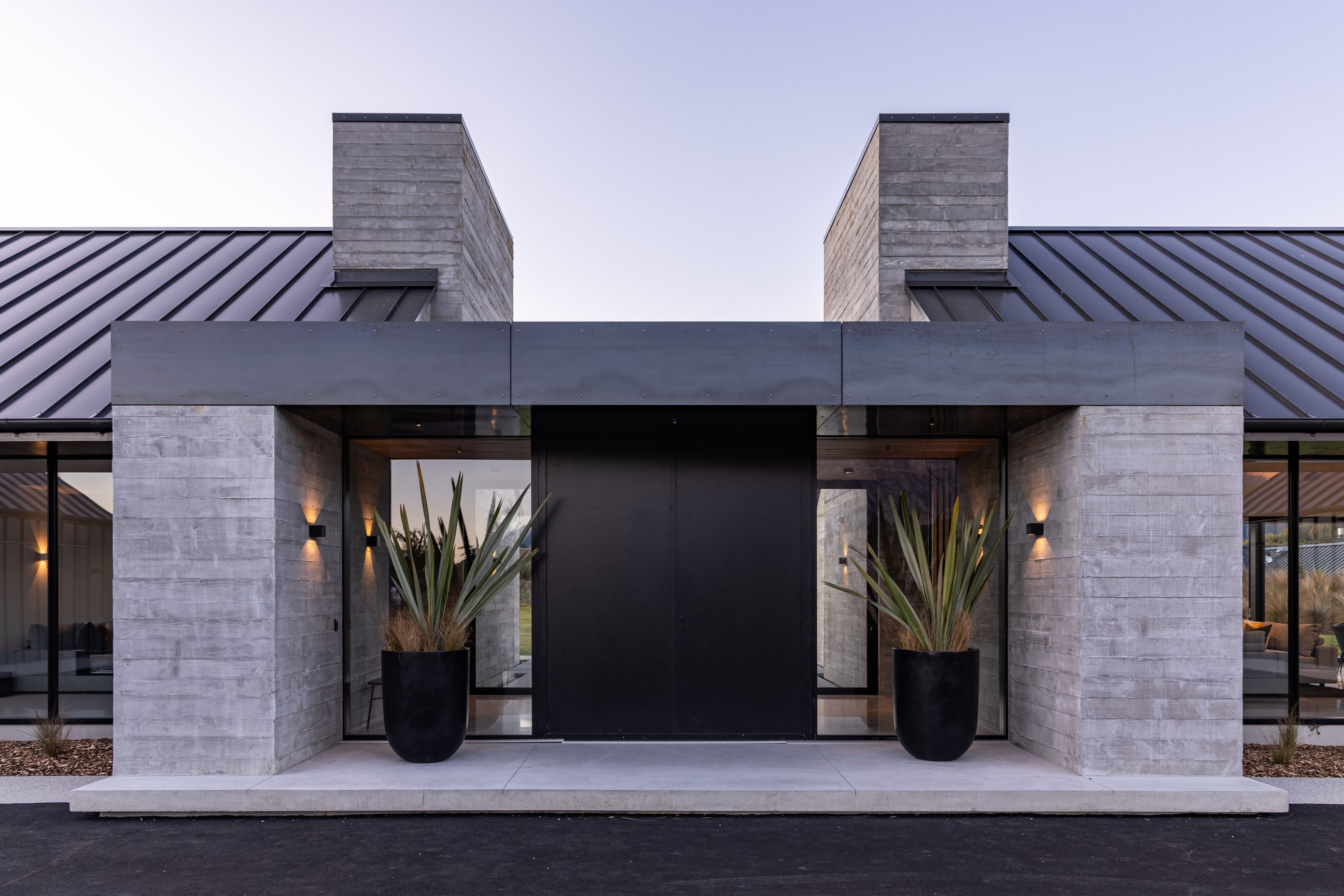 The entrance is centred, a large pivot door welcoming visitors to the home.