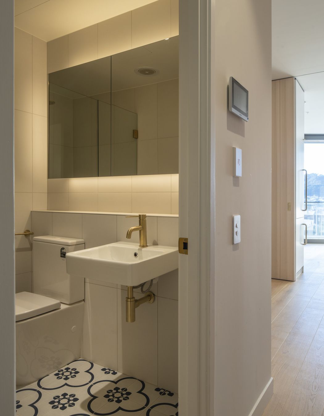 The compact bathroom features a decorative floor tile that lifts the space.