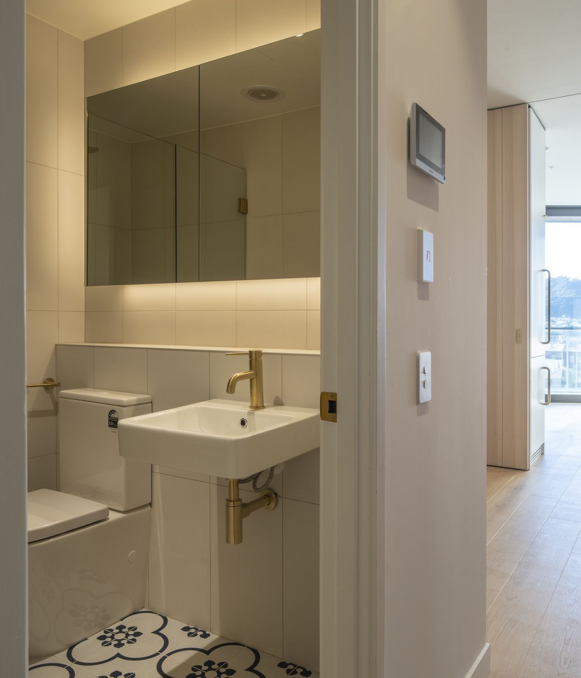The compact bathroom features a decorative floor tile that lifts the space.