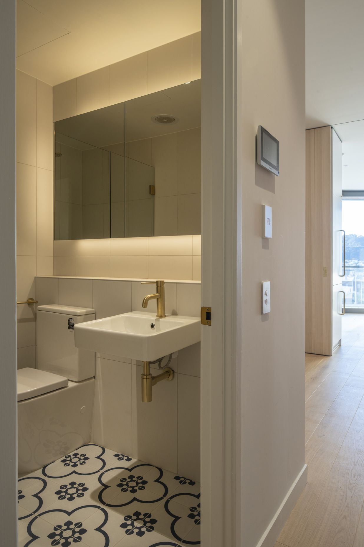 The compact bathroom features a decorative floor tile that lifts the space.