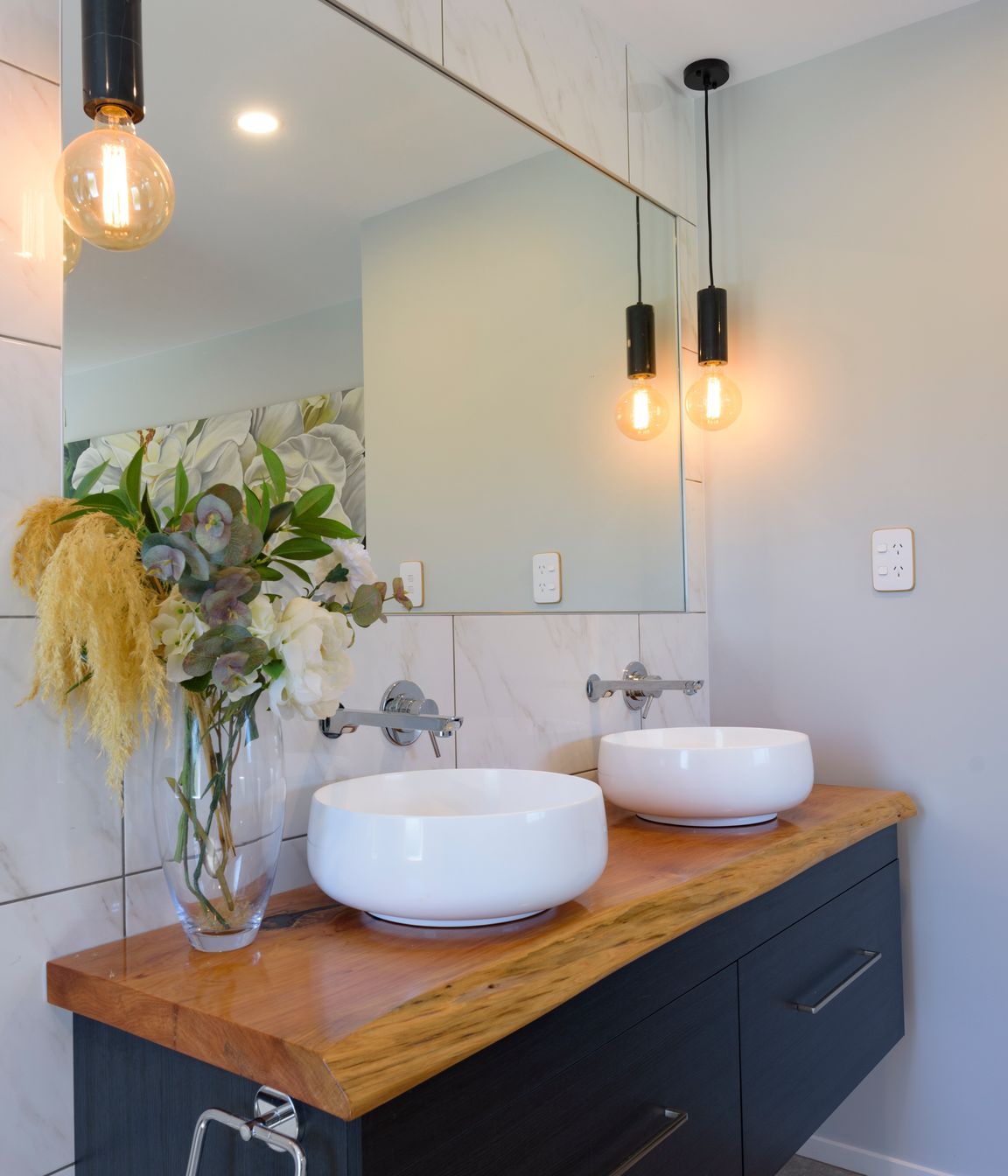Vanity top has been made from a macrocarpa slab by homeowner's father. The twin vessels are Athena Sirca Bowls and Mr Marble Bare Bulb pendants from Mr Ralph illuminate the room.