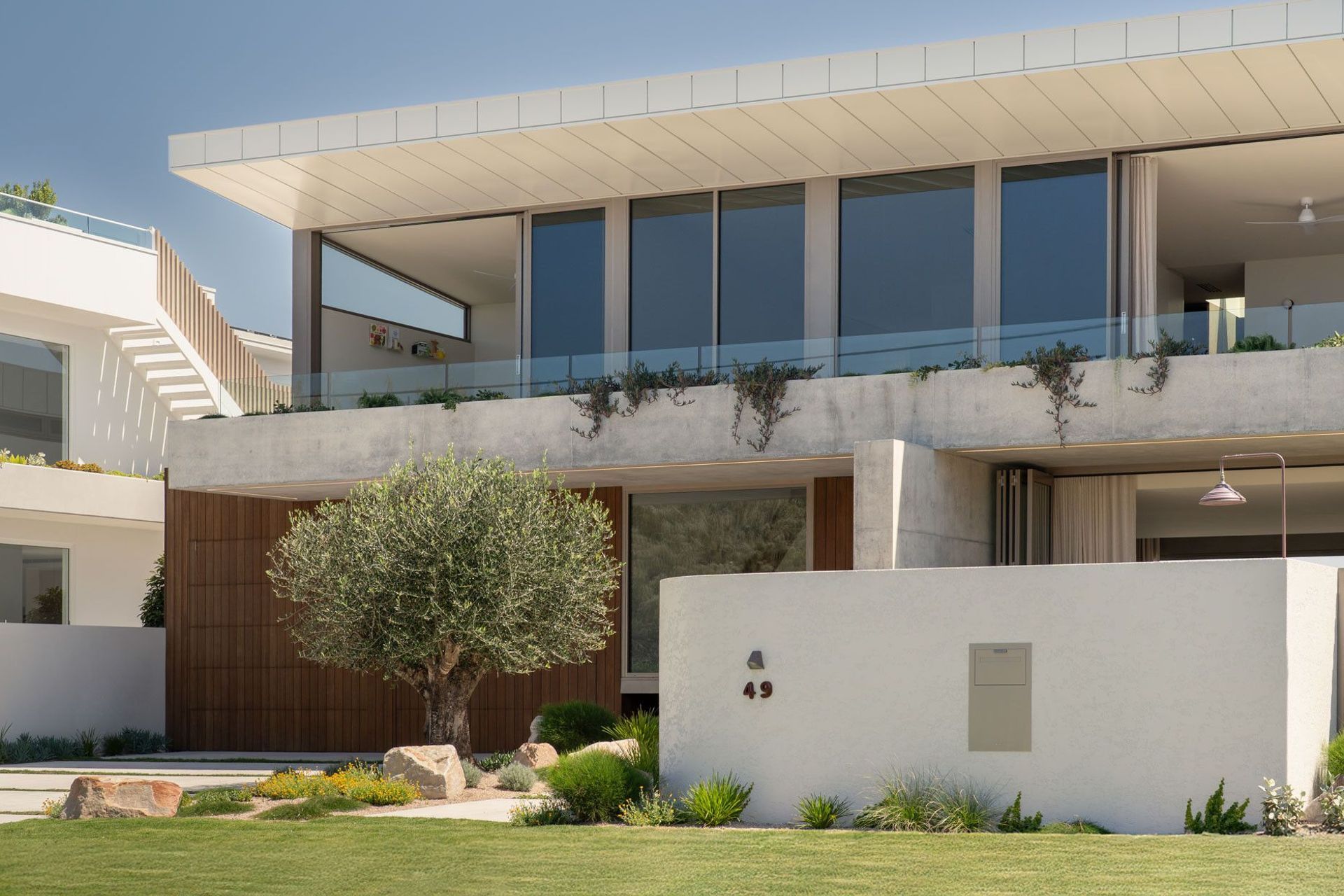 House on Pacific - Exterior. Front facade with a cantilevered roof, glass balustrade and landscaped garden wall.