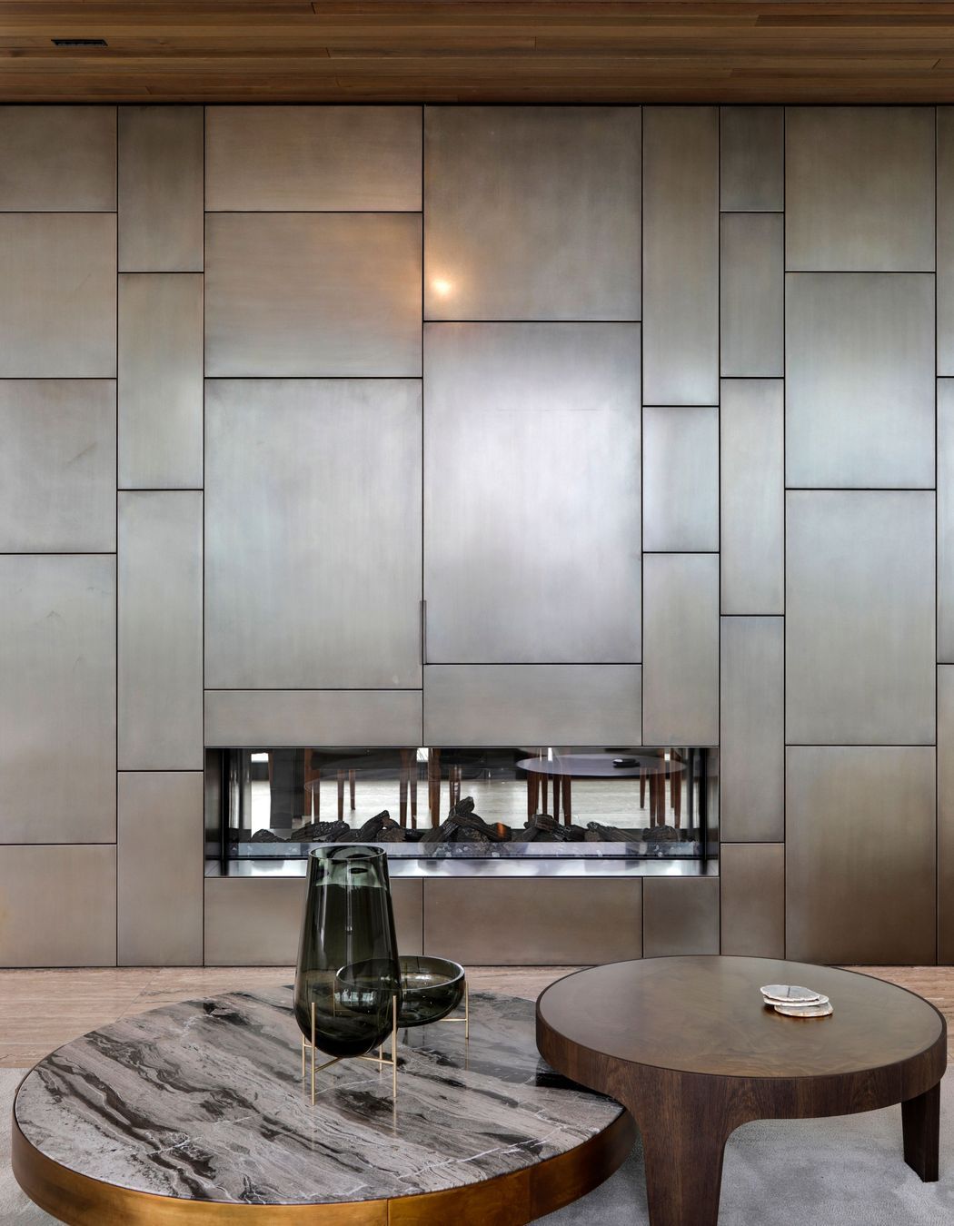 The aged bronze cladding on the fireplace is reflected in external copper elements.