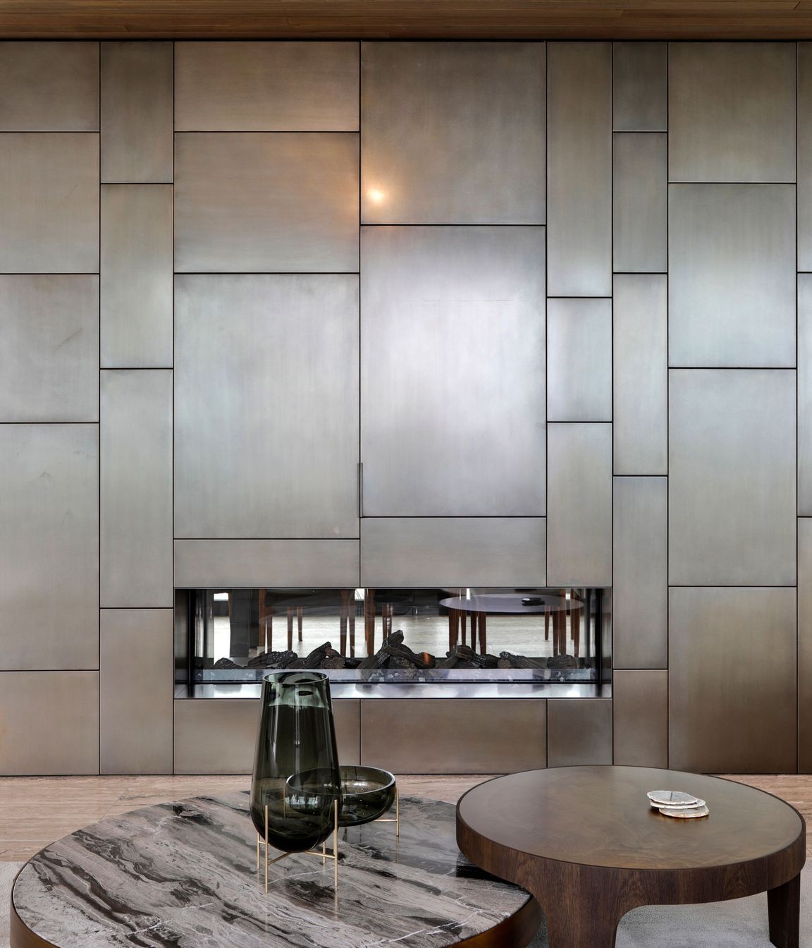 The aged bronze cladding on the fireplace is reflected in external copper elements.