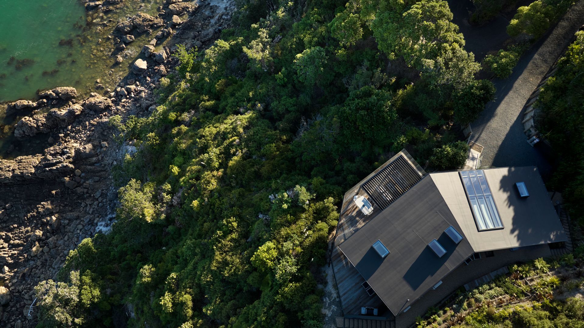 Nestled on the slopes of Mount Paku, Cliff Hanger captures sweeping views of Tairua Harbour and Slipper Island, appearing to hover above the rugged coastline 35 metres below. Its organic design mirrors the mountain’s natural contours, with a roof that til video
