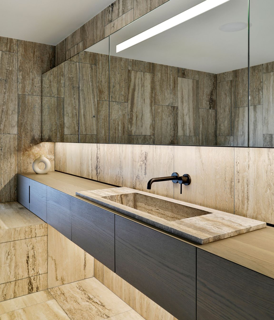 A bathroom continues the travertine materiality.