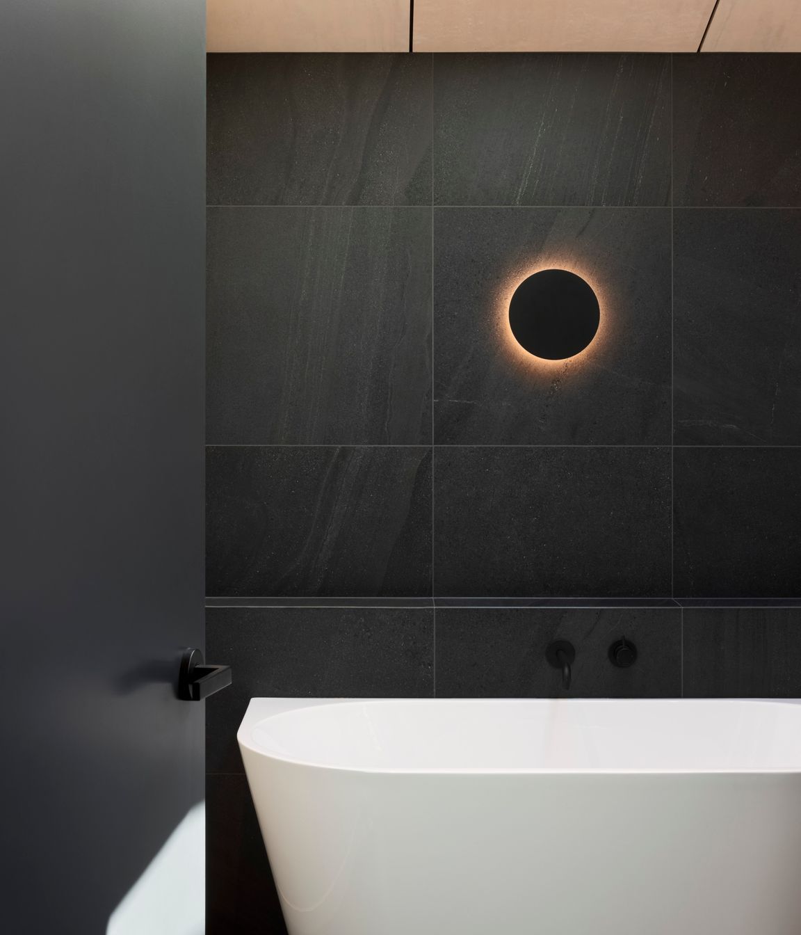 Natural timbers give way to dark stone tiles in the bathroom for a modern twist on the classic 'black and white' look.