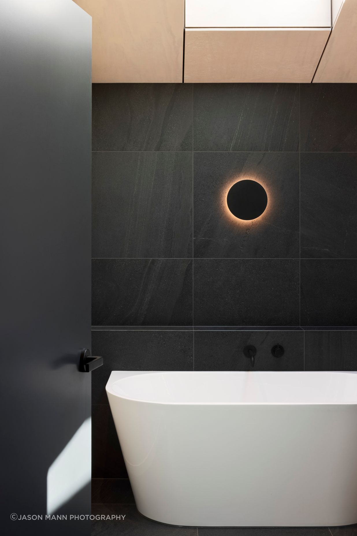 Natural timbers give way to dark stone tiles in the bathroom for a modern twist on the classic 'black and white' look.