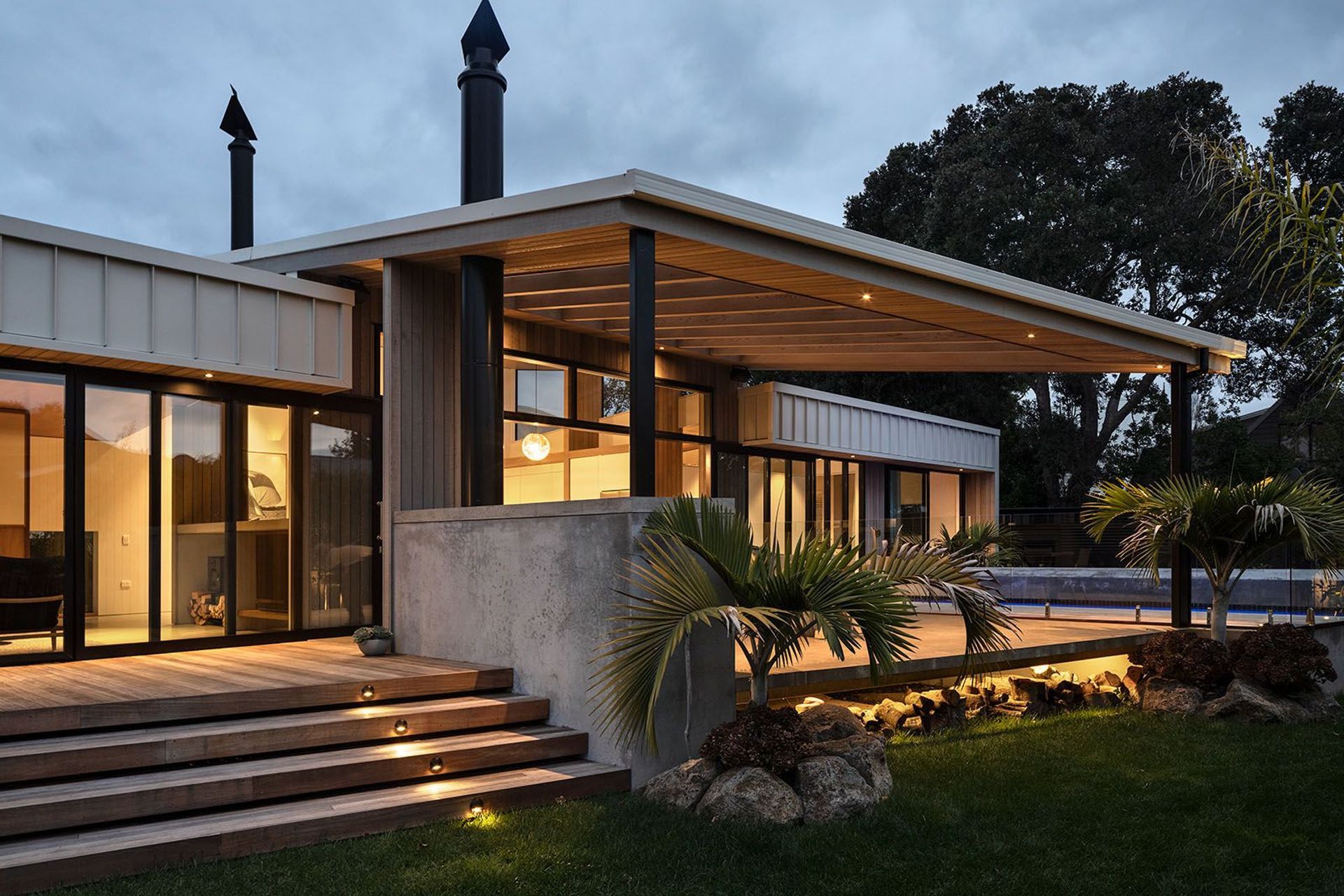 The outdoor living area is sheltered by a sail-like canopy with cedar-panelled soffit and a slatted shade.