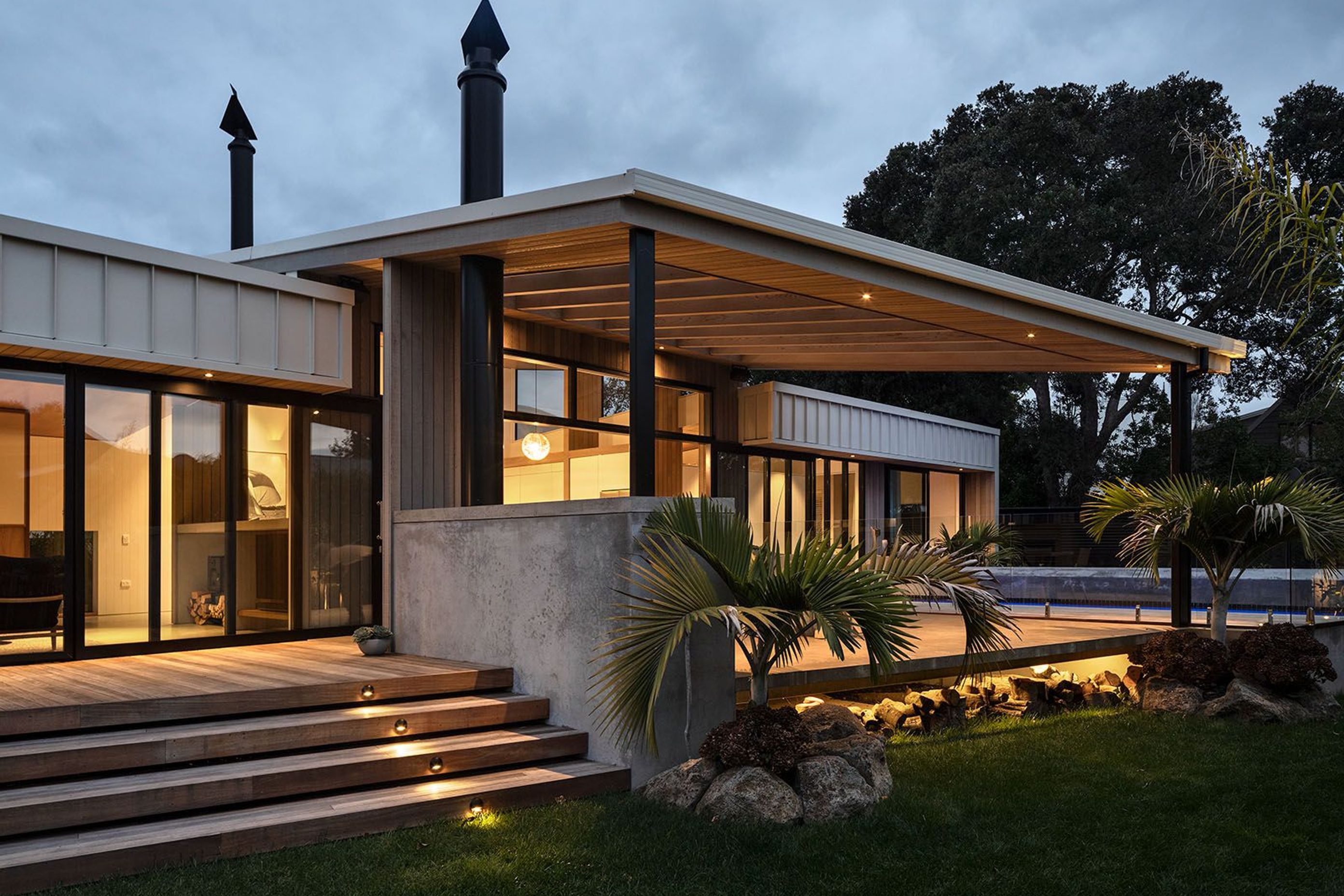The outdoor living area is sheltered by a sail-like canopy with cedar-panelled soffit and a slatted shade.