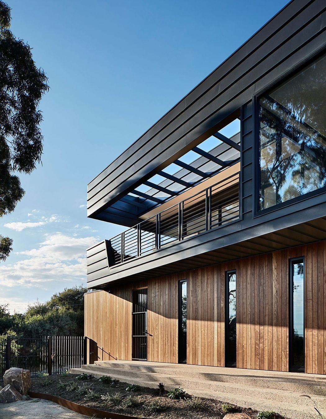 The solid timber cladding of the lower floor provides a base for the open air balcony above.