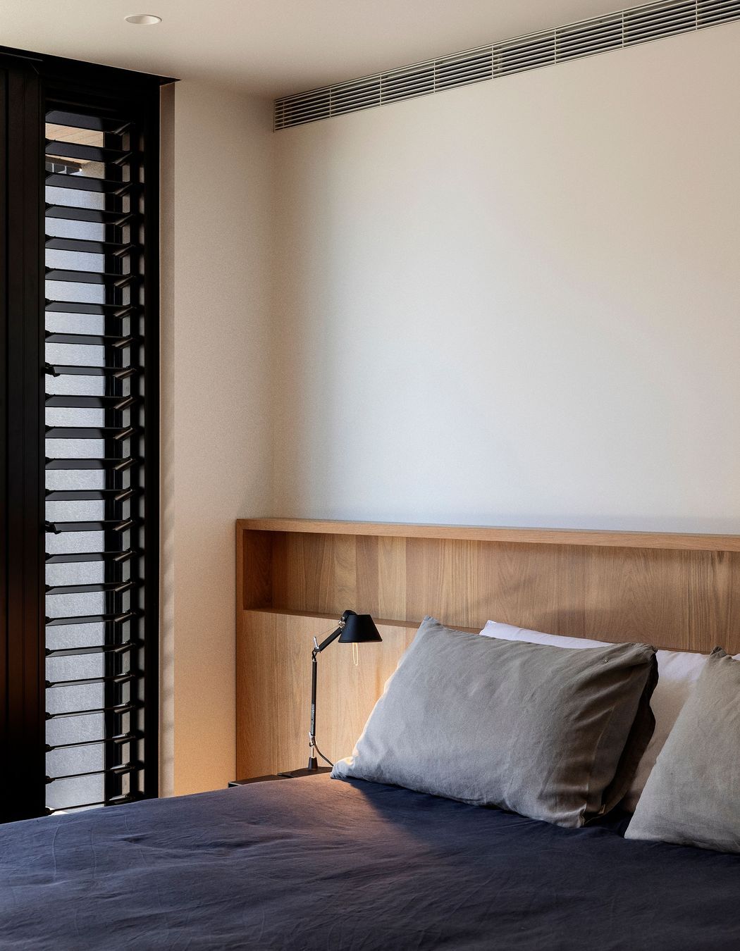 A built-in timber headboard in a guest room infuses it with warmth.