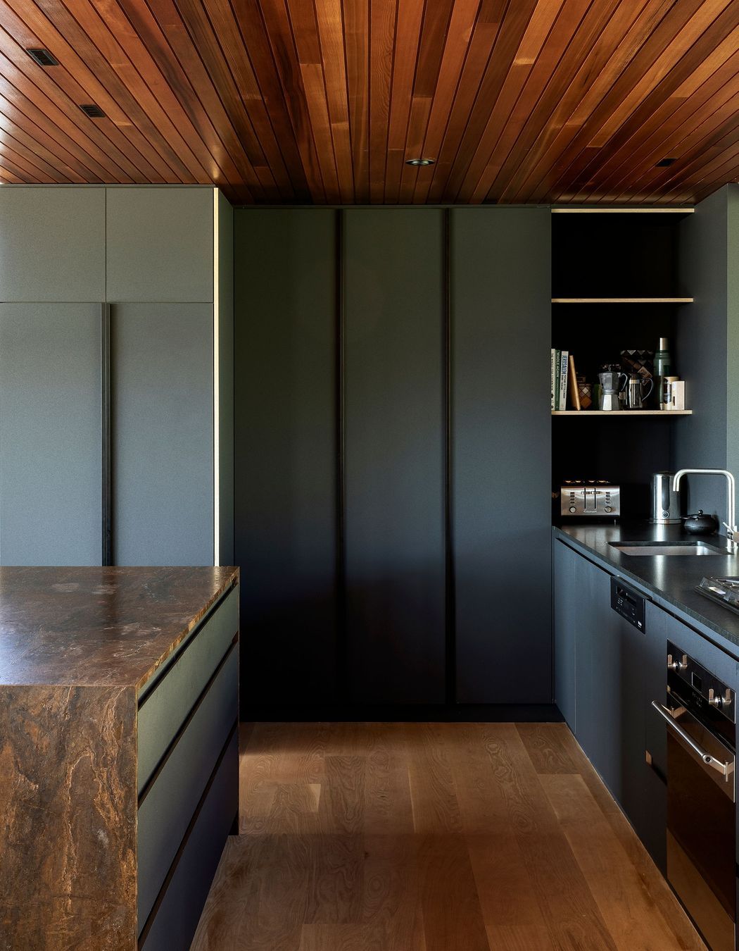 The bronzite benchtop and dark cabinetry give the kitchen a recessed and moody feel.