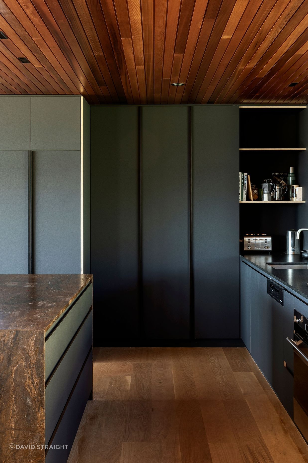 The bronzite benchtop and dark cabinetry give the kitchen a recessed and moody feel.