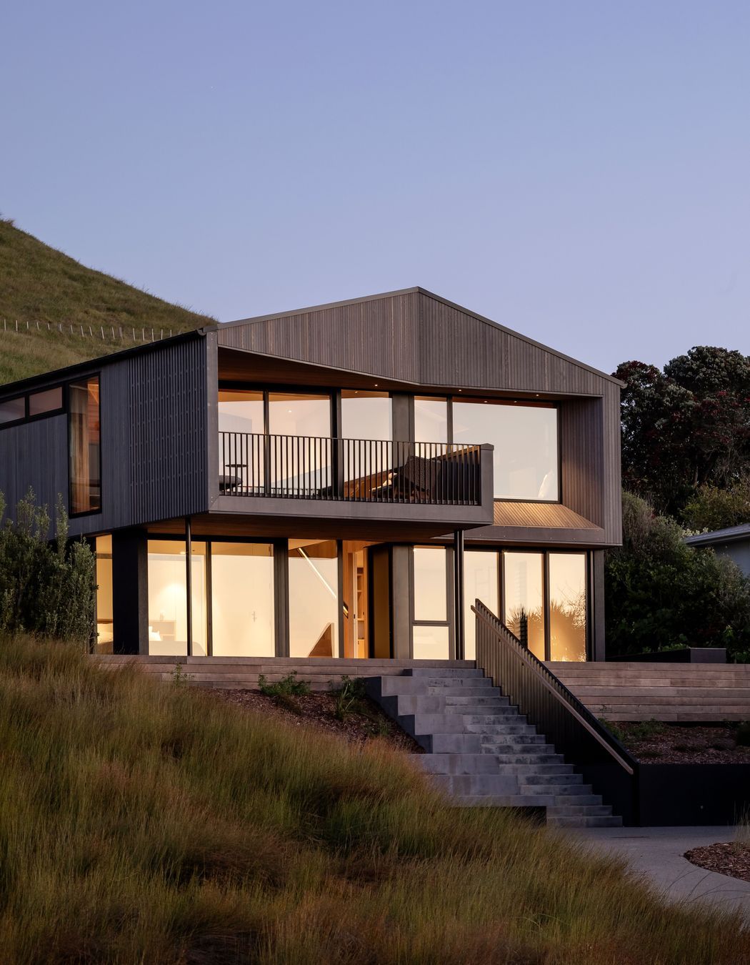 The dart shape of this Otama Beach holiday home recesses its form neatly into the hillside.
