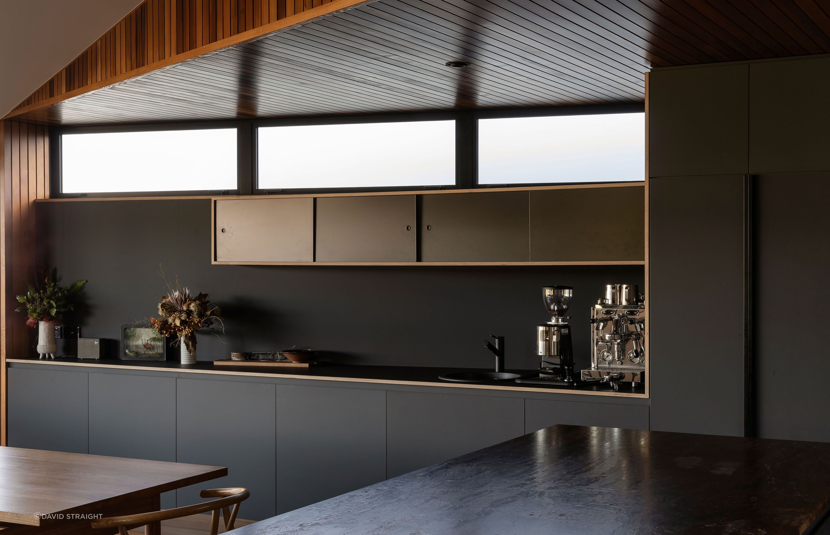 The dark kitchen cabinetry juxtaposes the warm and light interior.