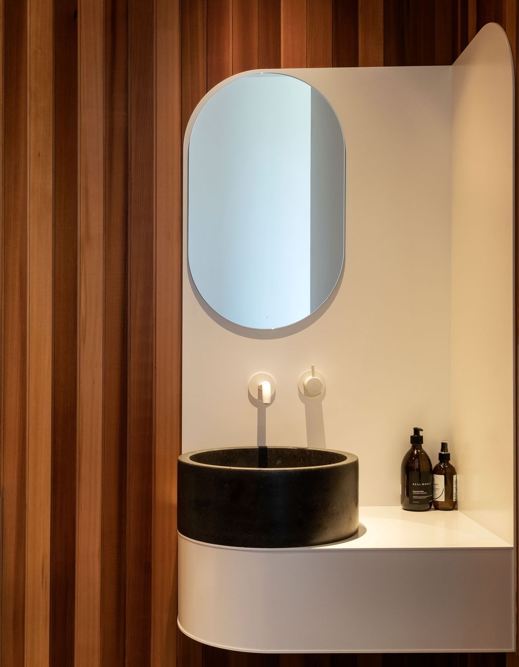 A curved powder room vanity provides the perfect foil for the timber wall lining.