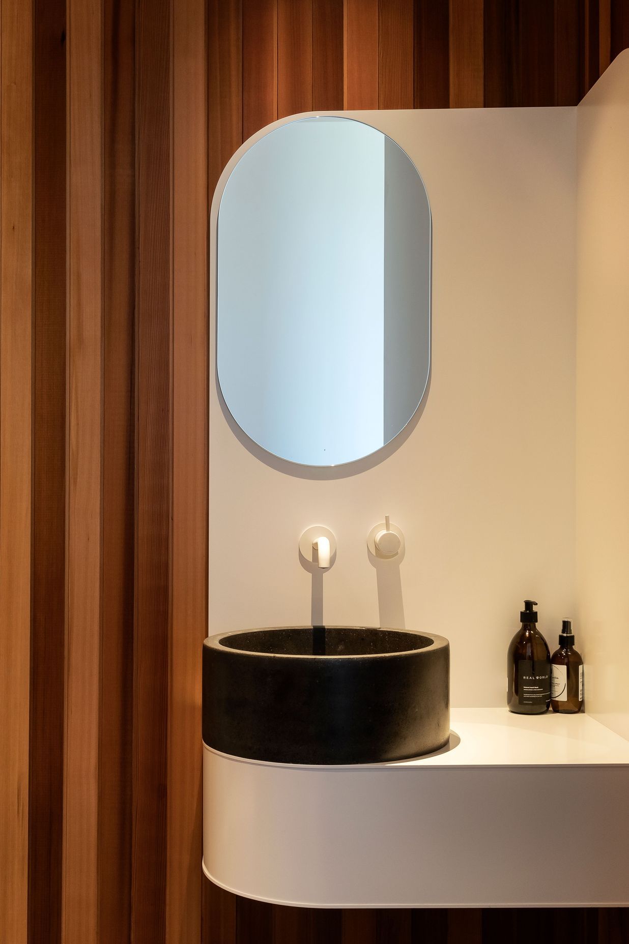 A curved powder room vanity provides the perfect foil for the timber wall lining.