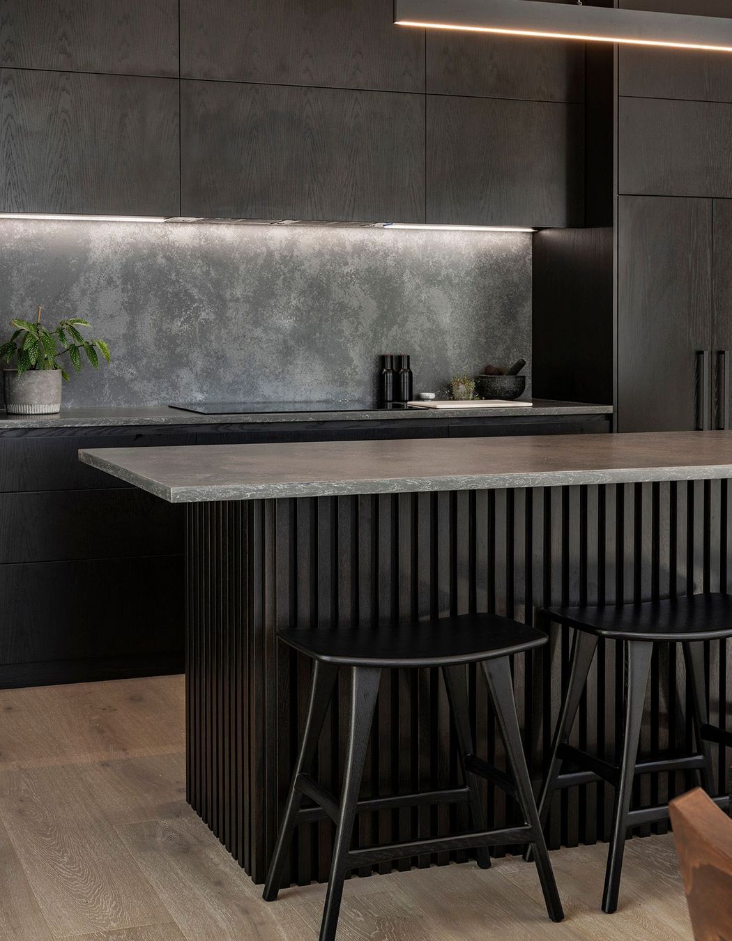 Dark tones contrast the sun bleached tones of the exterior. Cabinetry crafted by Finesse Joinery.