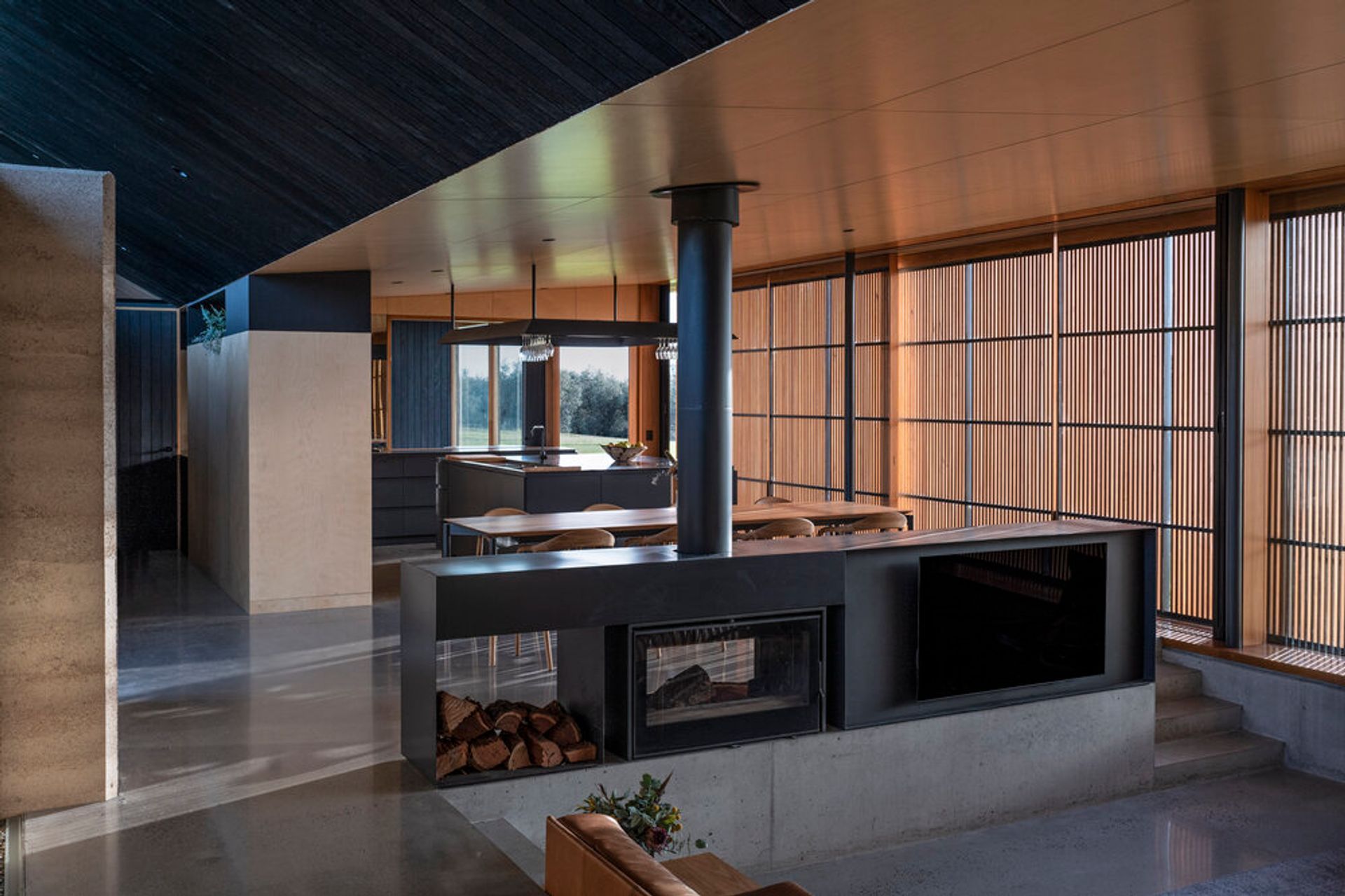 Unwind in style by the crackling fire: The mesmerizing Axis i1000 Freestanding Double Sided fireplace at Mystery Bay House creates a cozy sanctuary within the modern architectural marvel