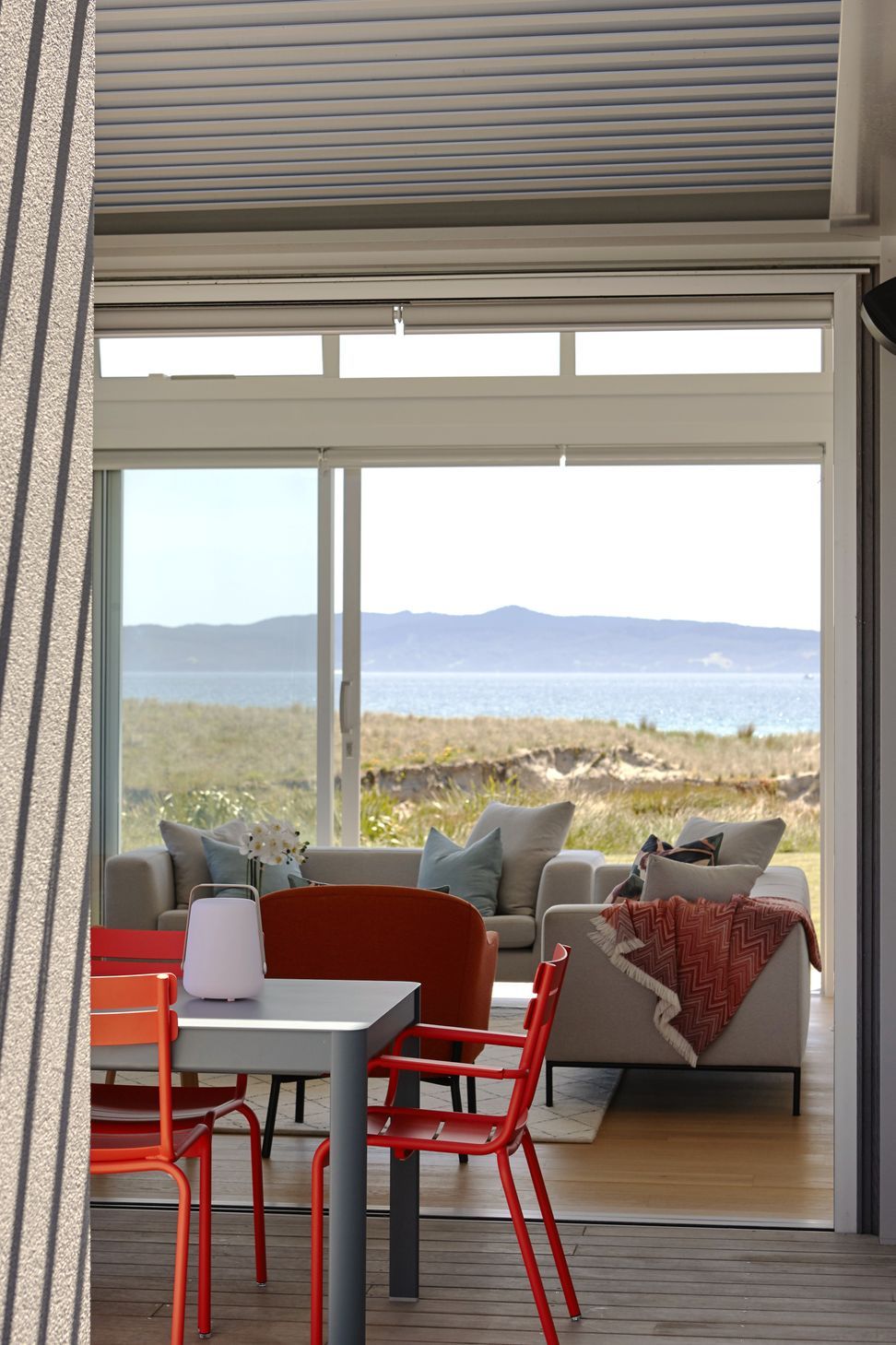 Standing beneath the covered outdoor terrace, the living room opens completely to the exterior, creating a seamless relationship between the home, the beach and the surrounding landscape.