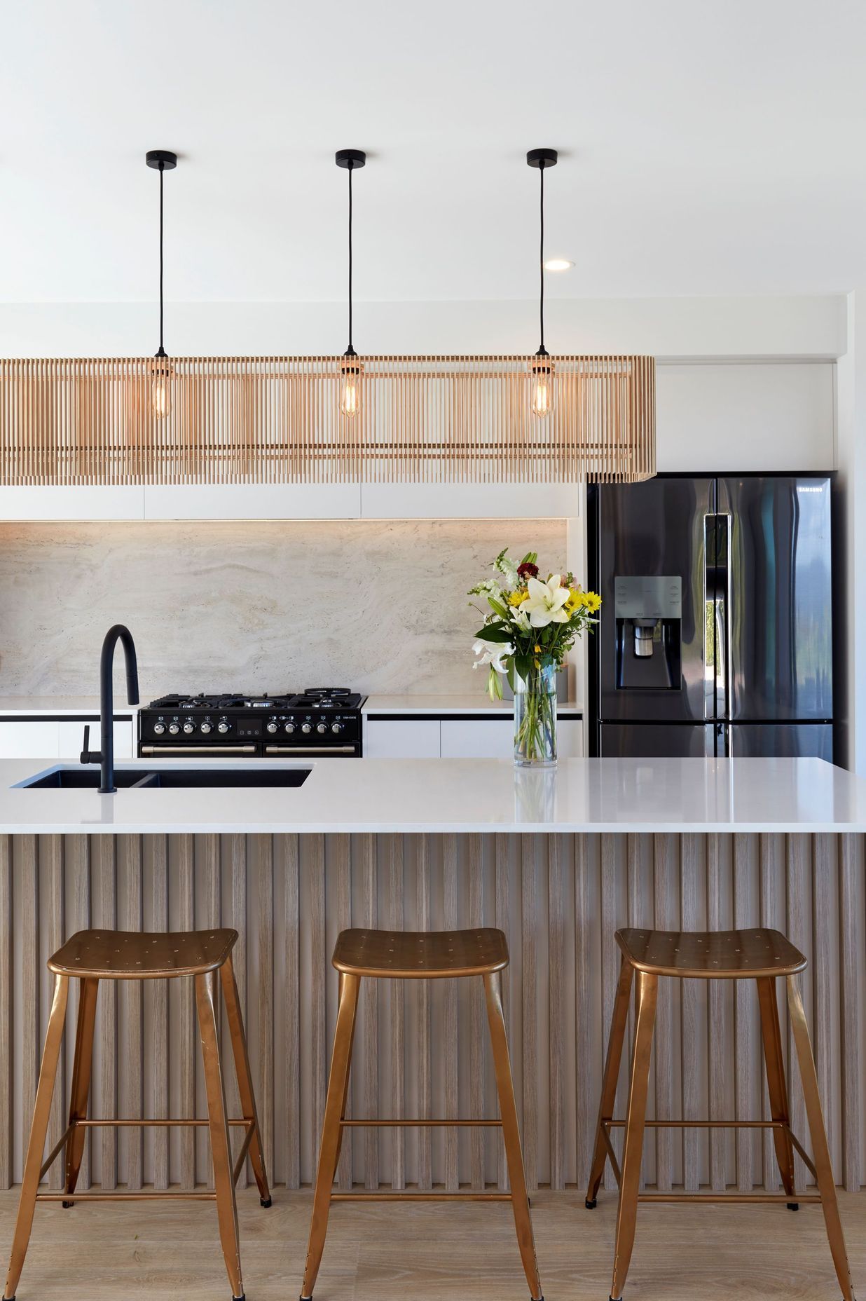 An i02 long rectangle shade follows the form of the kitchen island with its Silestone top and Decoform panelled front. The custom-designed splashback is a single large-format tile from Tile Space.