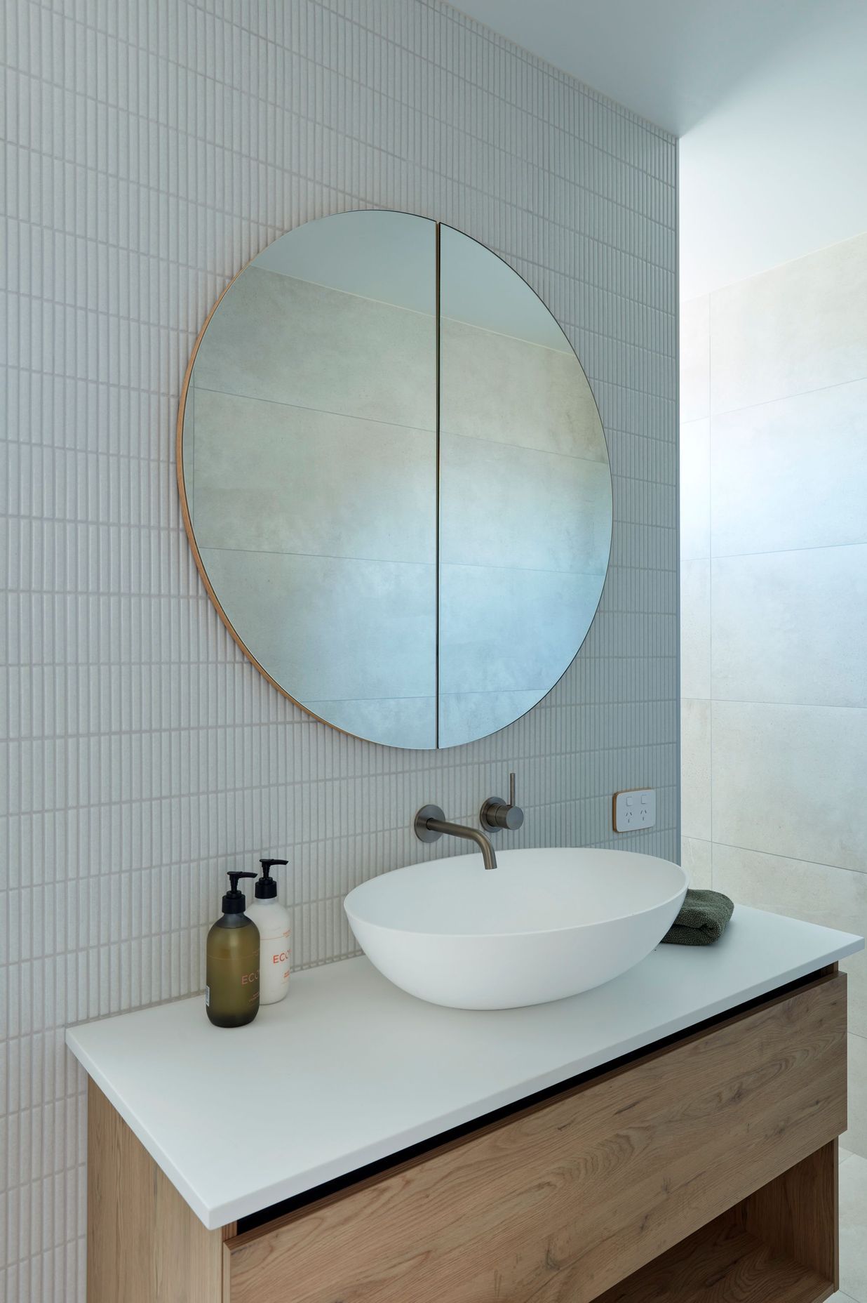 The owners chose a Progetto Vista mirror cabinet as a statement piece in the ensuite. It is mounted on a wall of glossy Yubi Sake finger mosaics above an Odessa Urban vessel basin. Elementi Uno tapware in brushed nickel is a finishing touch.