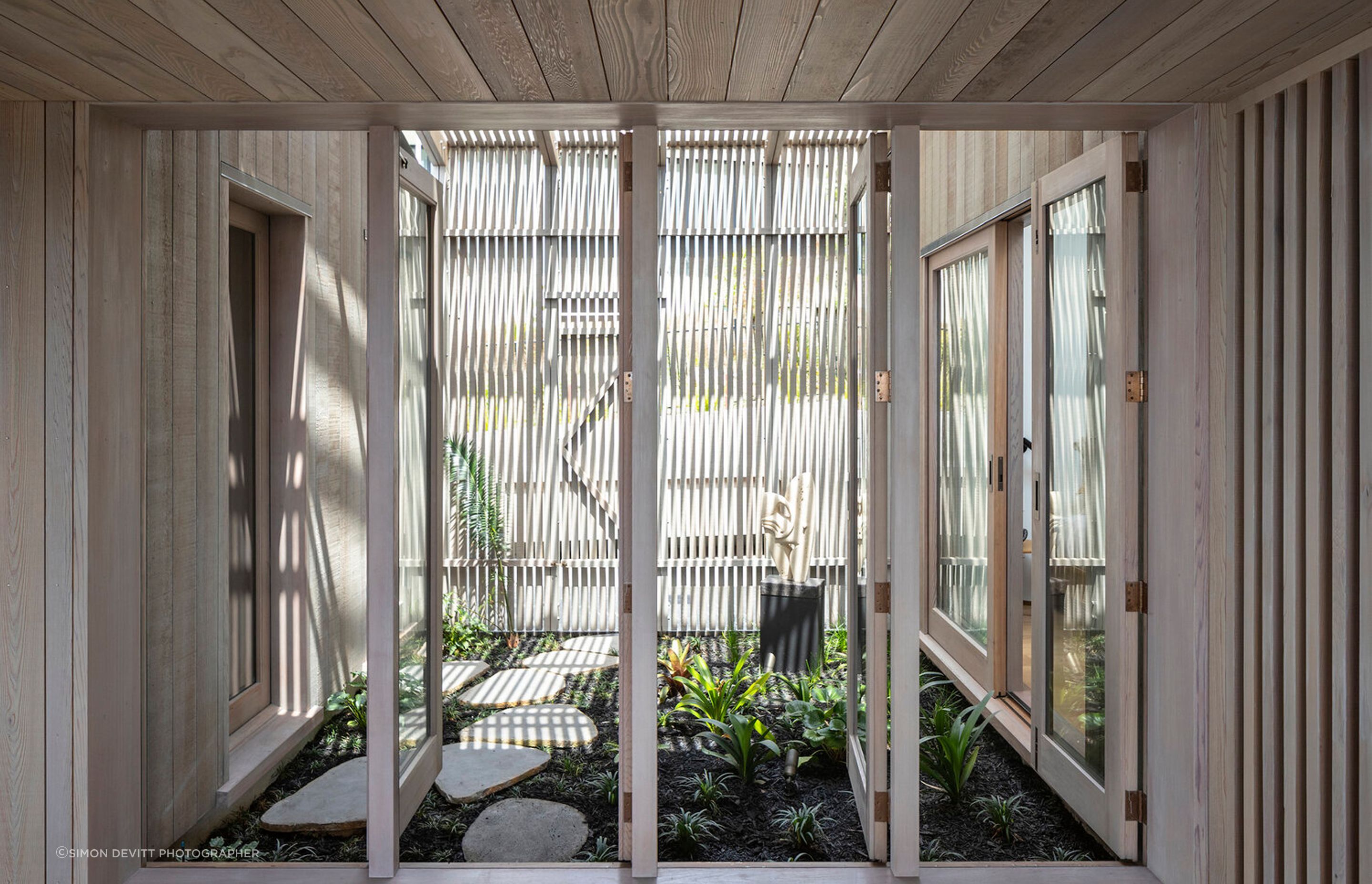 Internal doors access the courtyard, which features an open, slatted screen to allow for uninterrupted air flow.