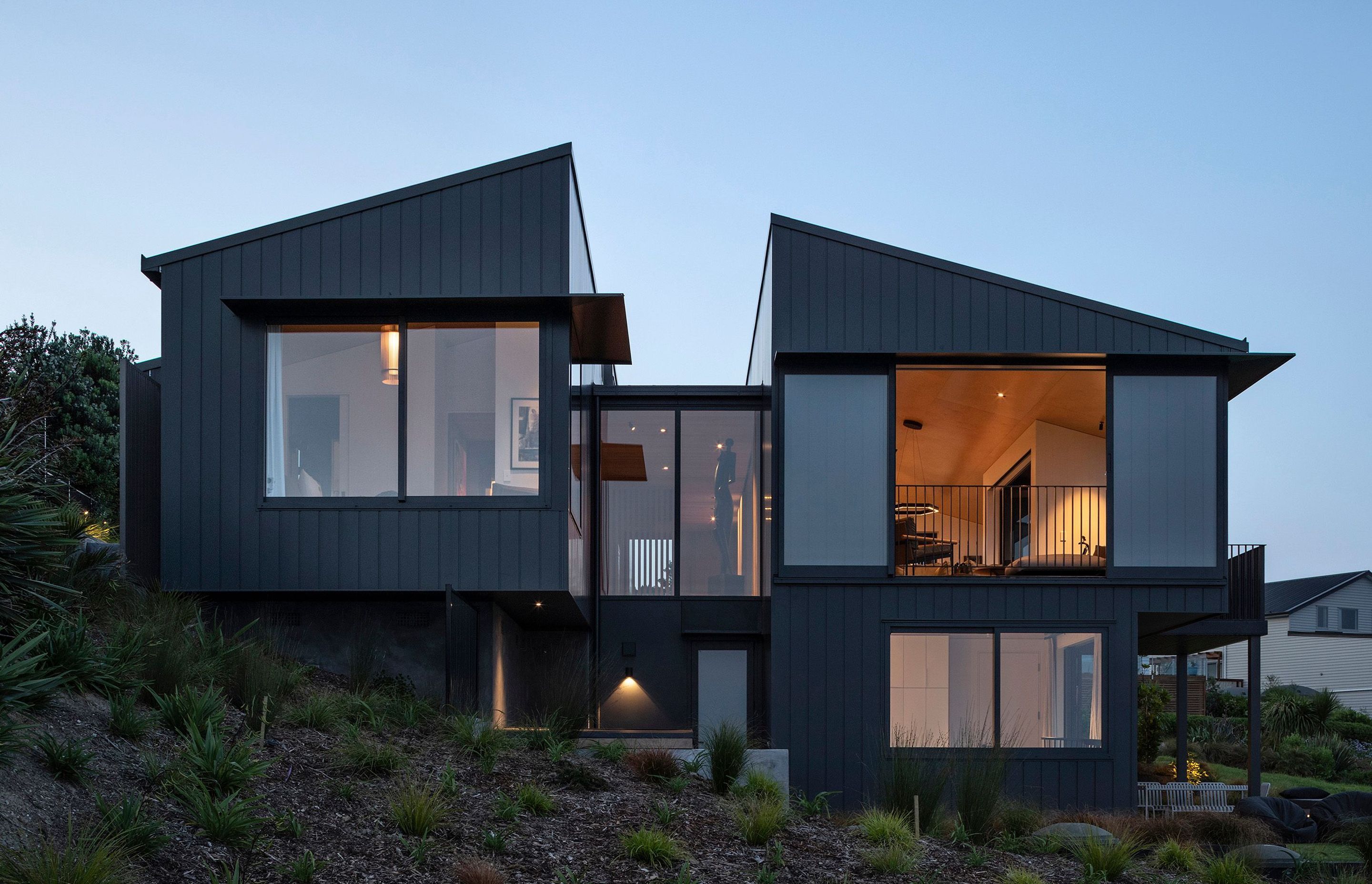 At dusk, the structure of the house seems to recede into the hillside, providing glimpses of the spaces inside.