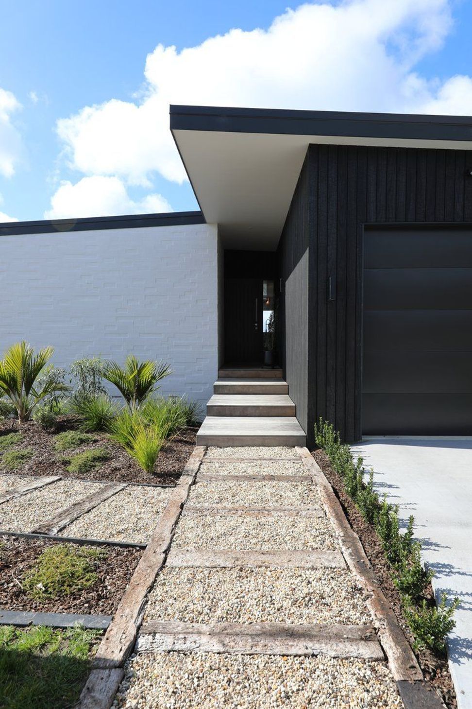 Snells Beach New-Build | Front entrance using bagged brick and ABODO Vulcan charred timber cladding with native planting.