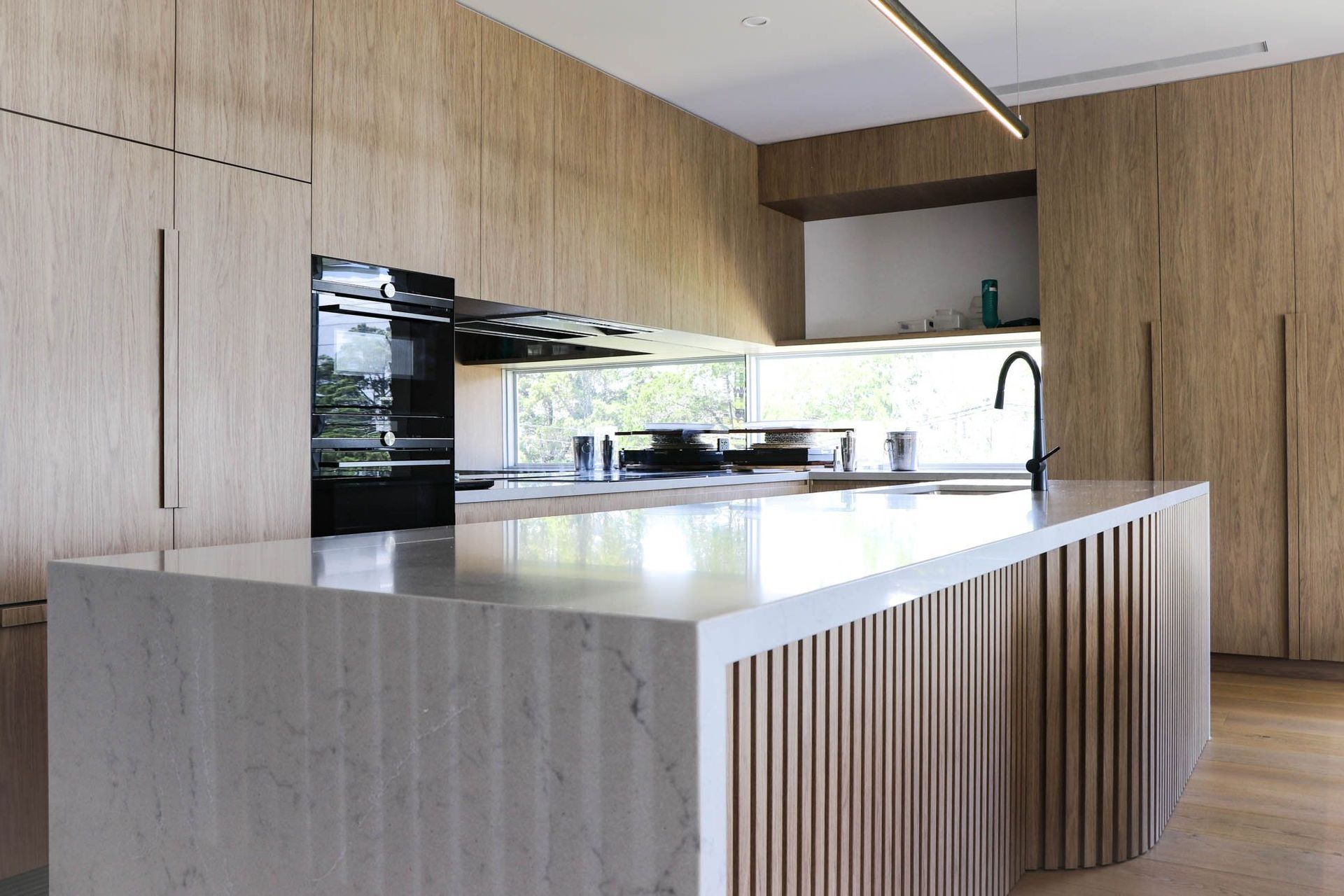 Shipp Residence - Kitchen. Stone waterfall island with timber battens and integrated appliances.
