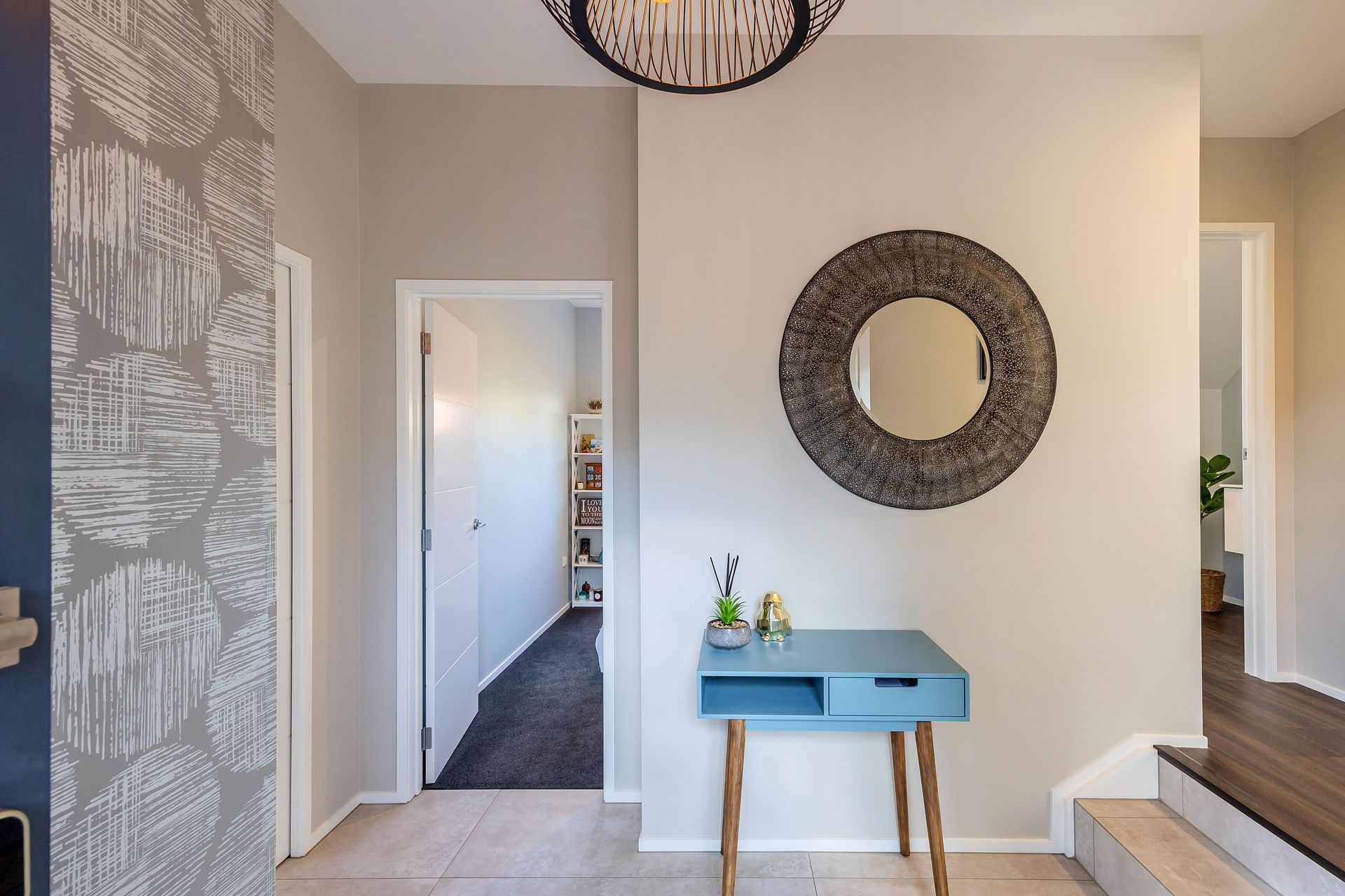 The entry foyer sets the tone for the rest of the home. It creates an initial impression and establishes the overall ambiance and style. We included an in-built closet to ensure that the space can remain cutter free, providing a designated space for belongings. We wanted to create a visual impact, by using a feature wallpaper and feature pendant light. The client found the mirror, which really sets the aesthetic tone for the rest of the interior. Aspiring Walls Focus Collection Spots &amp; Stripes Page 33 Pattern 30550-1 to feature wall Resene Alabaster to architraves &amp; skirting Resene Triple White Pointer to all walls and ceiling Gravity Pearl Porcelain Tile 600x1200 Matt to entry floor with grout colour Mapei Medium Grey 112 (Tile layout: straight stack)