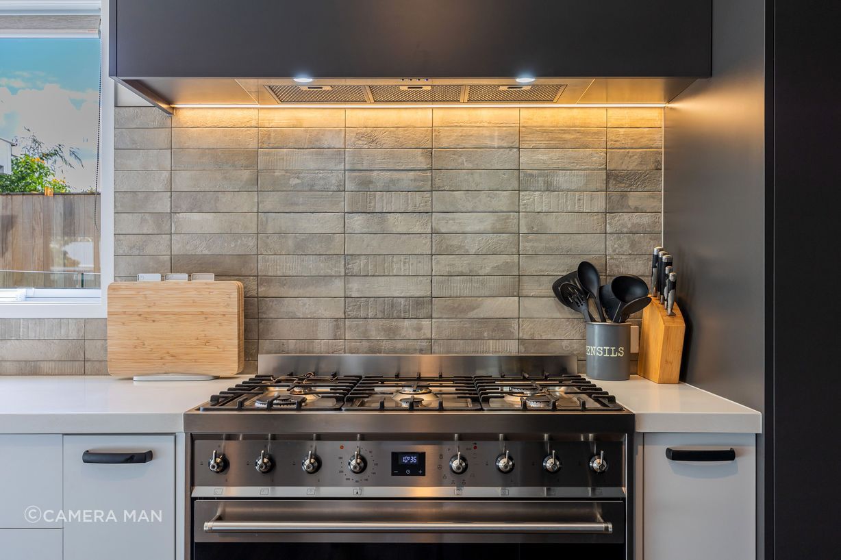 Eurostone Breeze Blanc to benchtop; Prime Melamine Ironsand to kitchen high wall & overhead cabinetry; Emil Ceramica Kotto Cenere Brick 60x250 to kitchen splashback (with grout colour Mapei Cement 113) Tile layout: straight stack; Tile set-out: from centre of wall; Prime Melamine White to kitchen under bench cabinetry; Resene Alabaster to ceiling, architraves & skirting; Resene Triple White Pointer to all walls; Moduleo Transform Falcon Wood 28890 196x1320 to floor