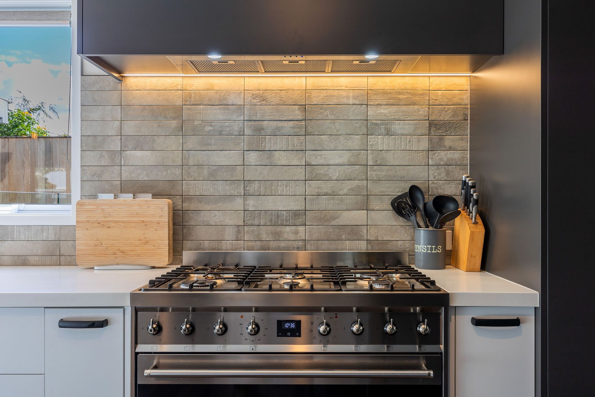 Eurostone Breeze Blanc to benchtop; Prime Melamine Ironsand to kitchen high wall &amp; overhead cabinetry; Emil Ceramica Kotto Cenere Brick 60x250 to kitchen splashback (with grout colour Mapei Cement 113) Tile layout: straight stack; Tile set-out: from centre of wall; Prime Melamine White to kitchen under bench cabinetry; Resene Alabaster to ceiling, architraves &amp; skirting; Resene Triple White Pointer to all walls; Moduleo Transform Falcon Wood 28890 196x1320 to floor