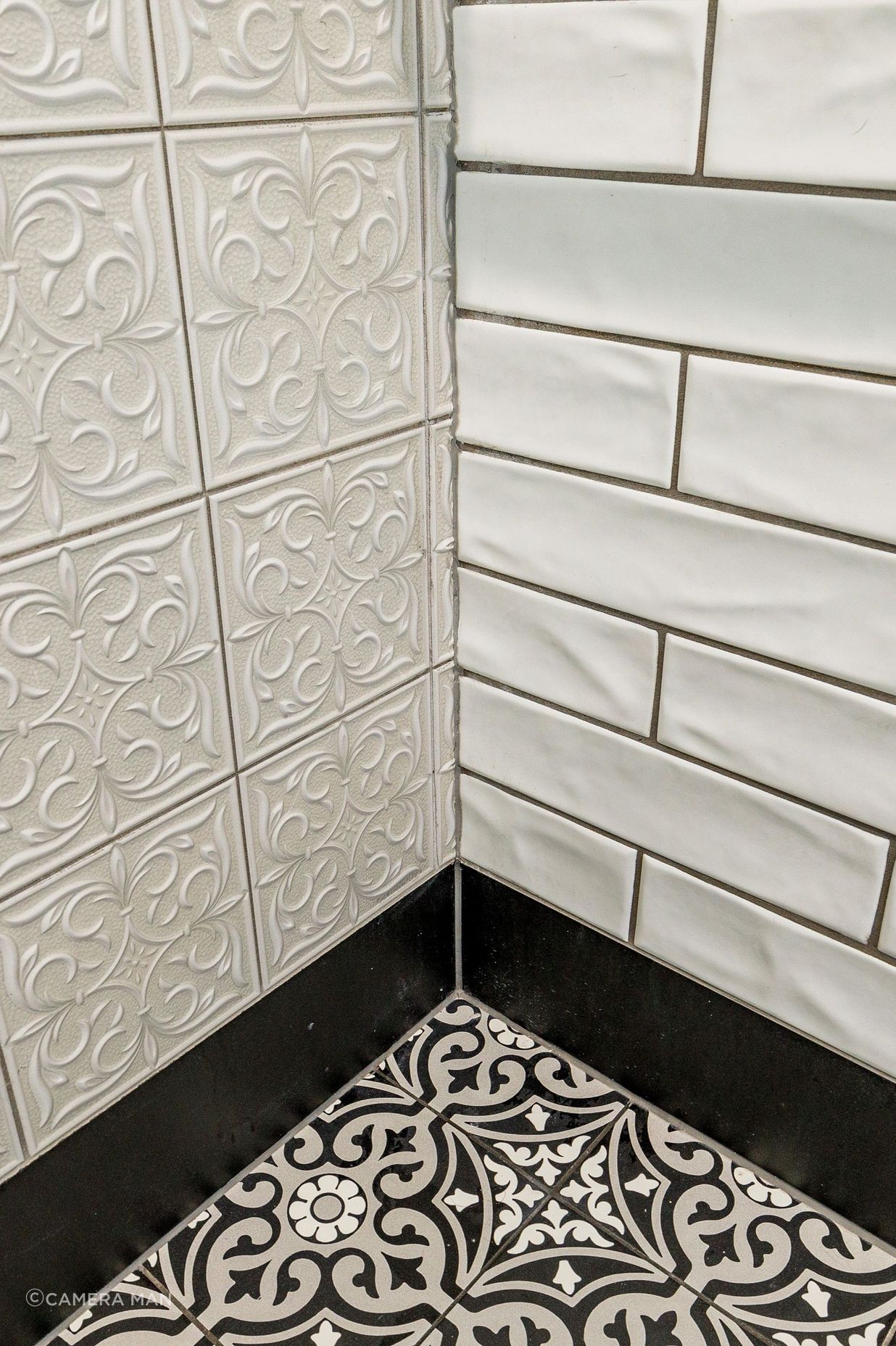 In this black &amp; white bathroom the goal was to create a traditional charm. The floor tiles are Tile Warehouse - Element - Arabesque with the skirt tile Tile Warehouse -Pure Black Matt. The textured subway tiles are Tile Space - MT1366 - Marlow Cloud Gloss and the decorative antique embossed pattern tile is Tile Depot - Antigua Muse White.