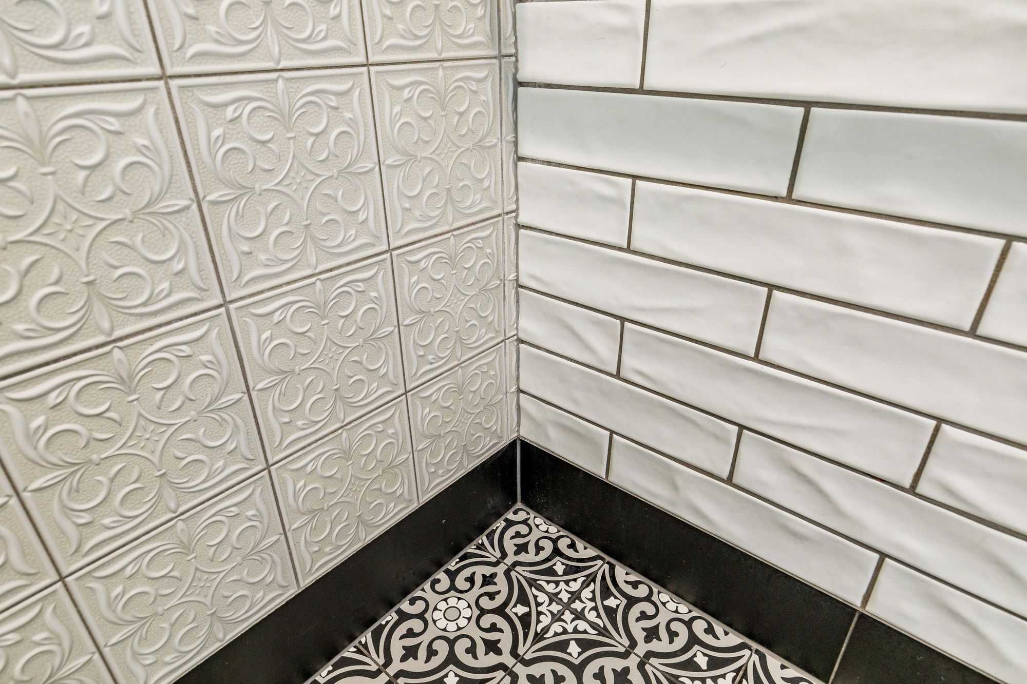 In this black & white bathroom the goal was to create a traditional charm. The floor tiles are Tile Warehouse - Element - Arabesque with the skirt tile Tile Warehouse -Pure Black Matt. The textured subway tiles are Tile Space - MT1366 - Marlow Cloud Gloss and the decorative antique embossed pattern tile is Tile Depot - Antigua Muse White.
