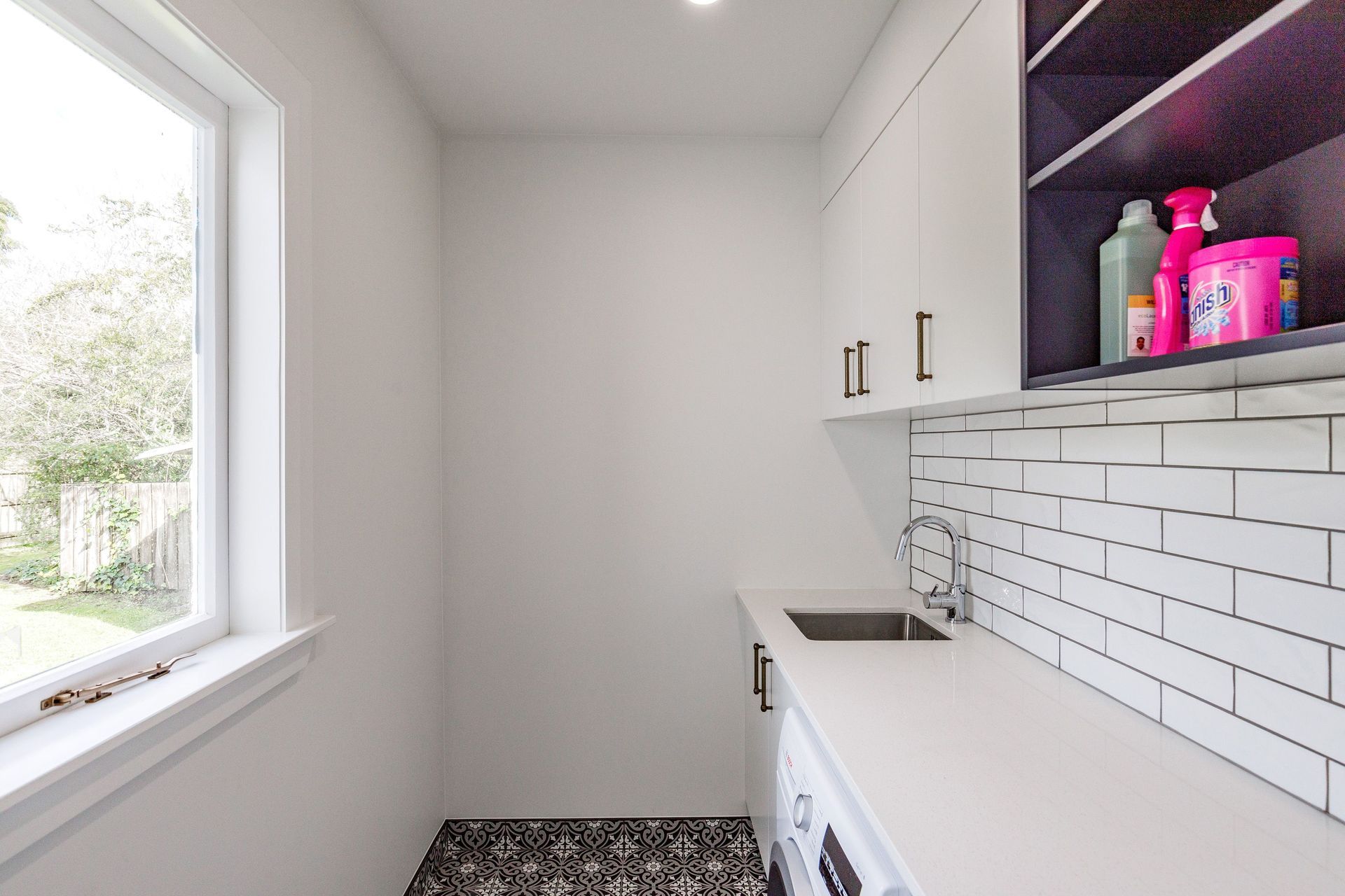 Ensuring complementary and cohesive changes to each of the spaces the laundry received cabinetry to match the kitchen finishes and handle selection. The floor tiles are Tile Warehouse - Element - Arabesque with the skirt tile Tile Warehouse -Pure Black Matt to mirror the en-suite. The textured subway tiles used for the splash-back are Tile Space - MT1366 - Marlow Cloud Gloss.