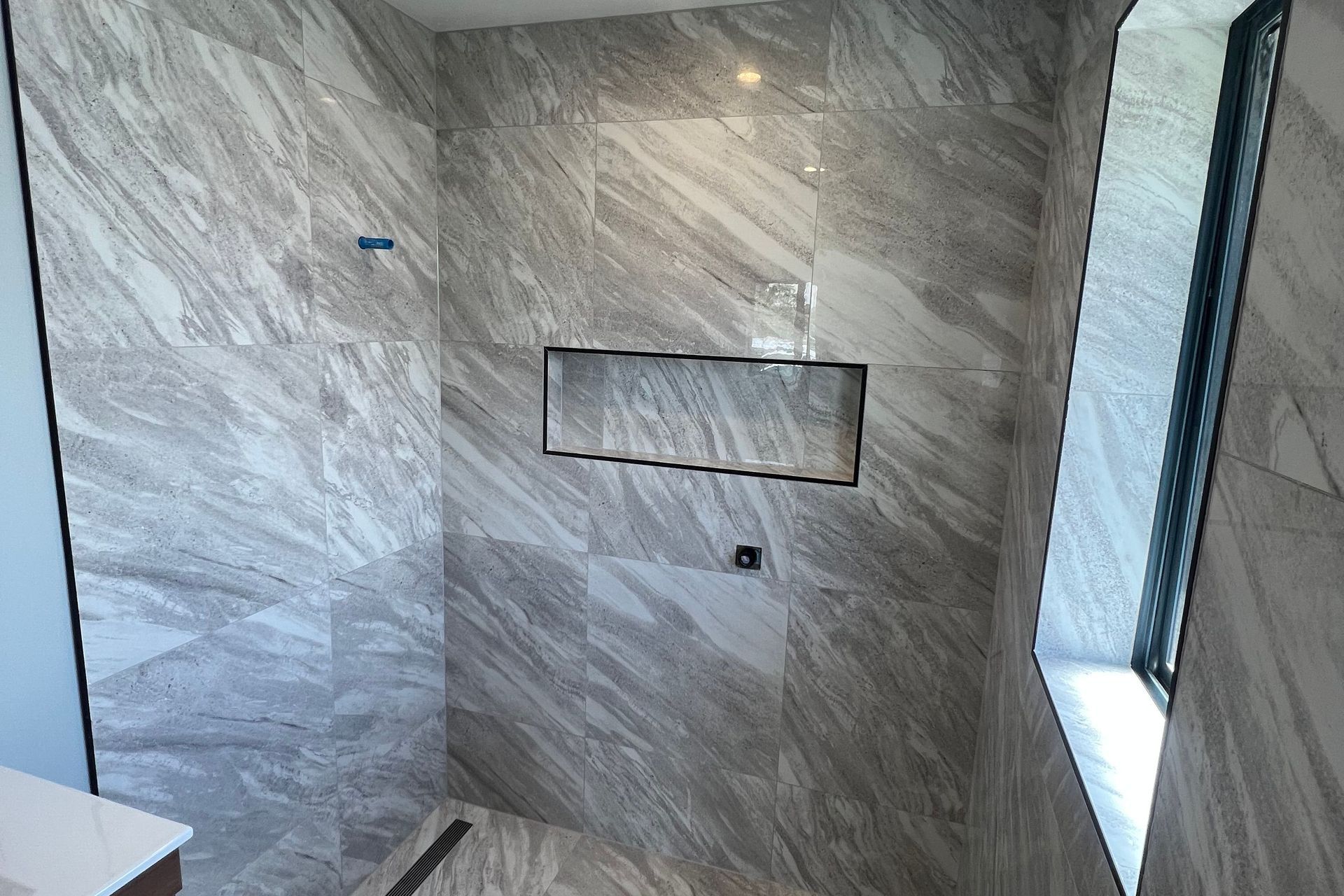 Tiled shower, wall, floor, niche &amp; window reveal.