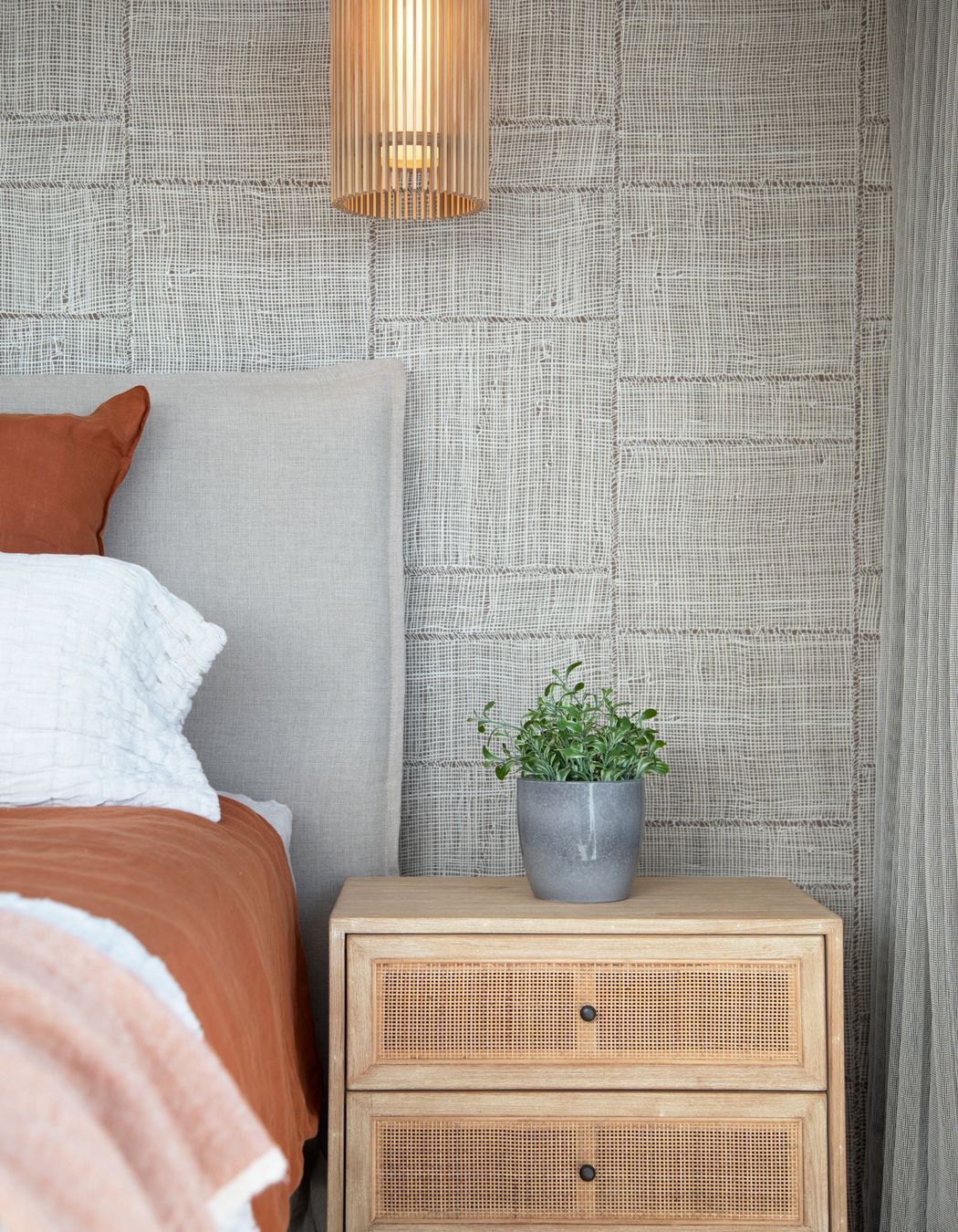 Rust bedroom with feature wallpaper, lighting and rattan bedside tables. Photographer - Sandra Henderson