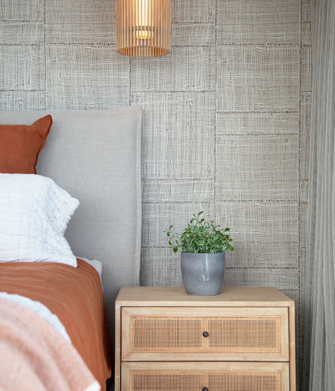 Rust bedroom with feature wallpaper, lighting and rattan bedside tables. Photographer - Sandra Henderson