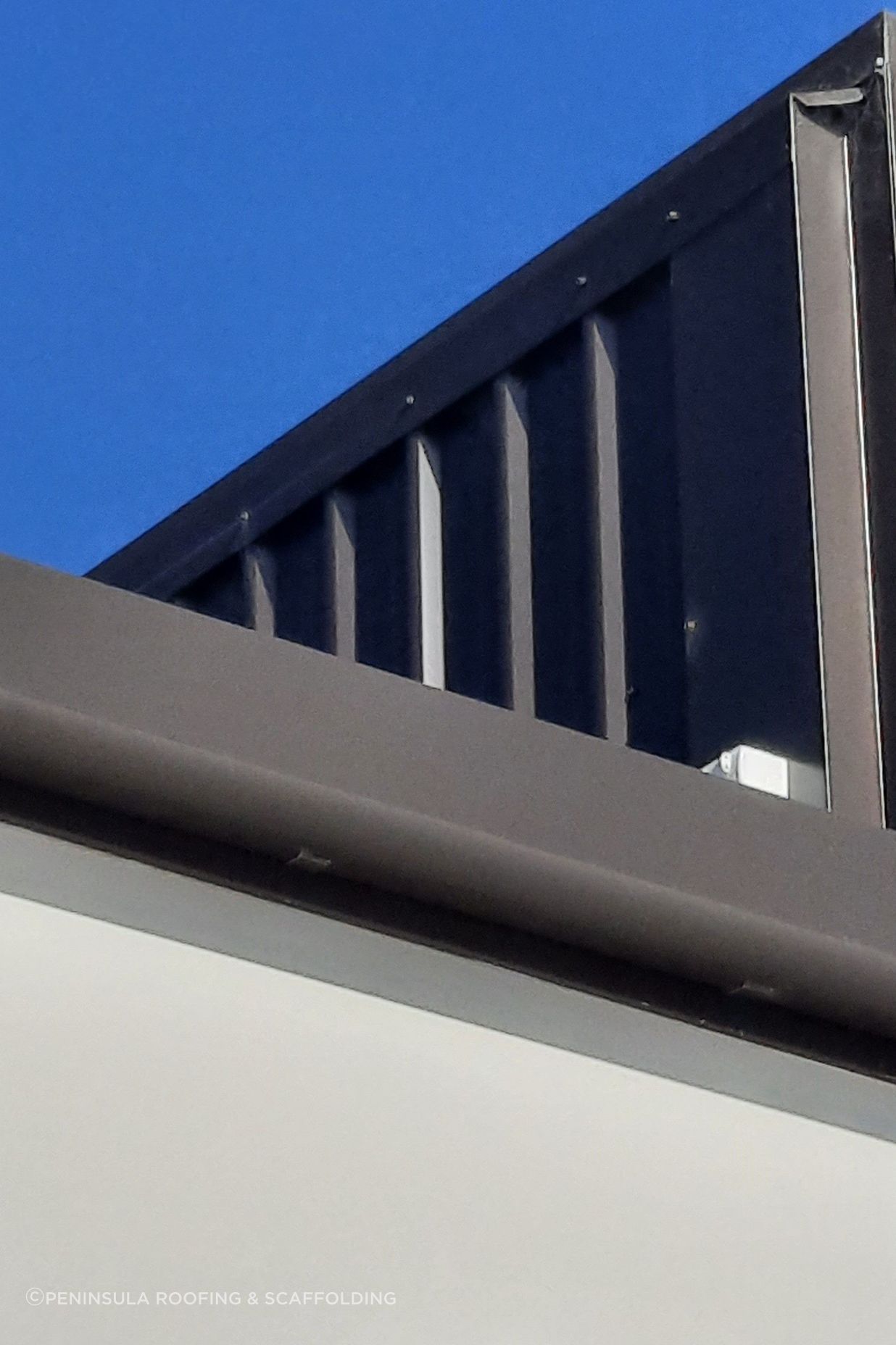 Detail of 175 Industrial Gutter “Ironsand” and vertical wall cladding to a precast concrete parapet wall