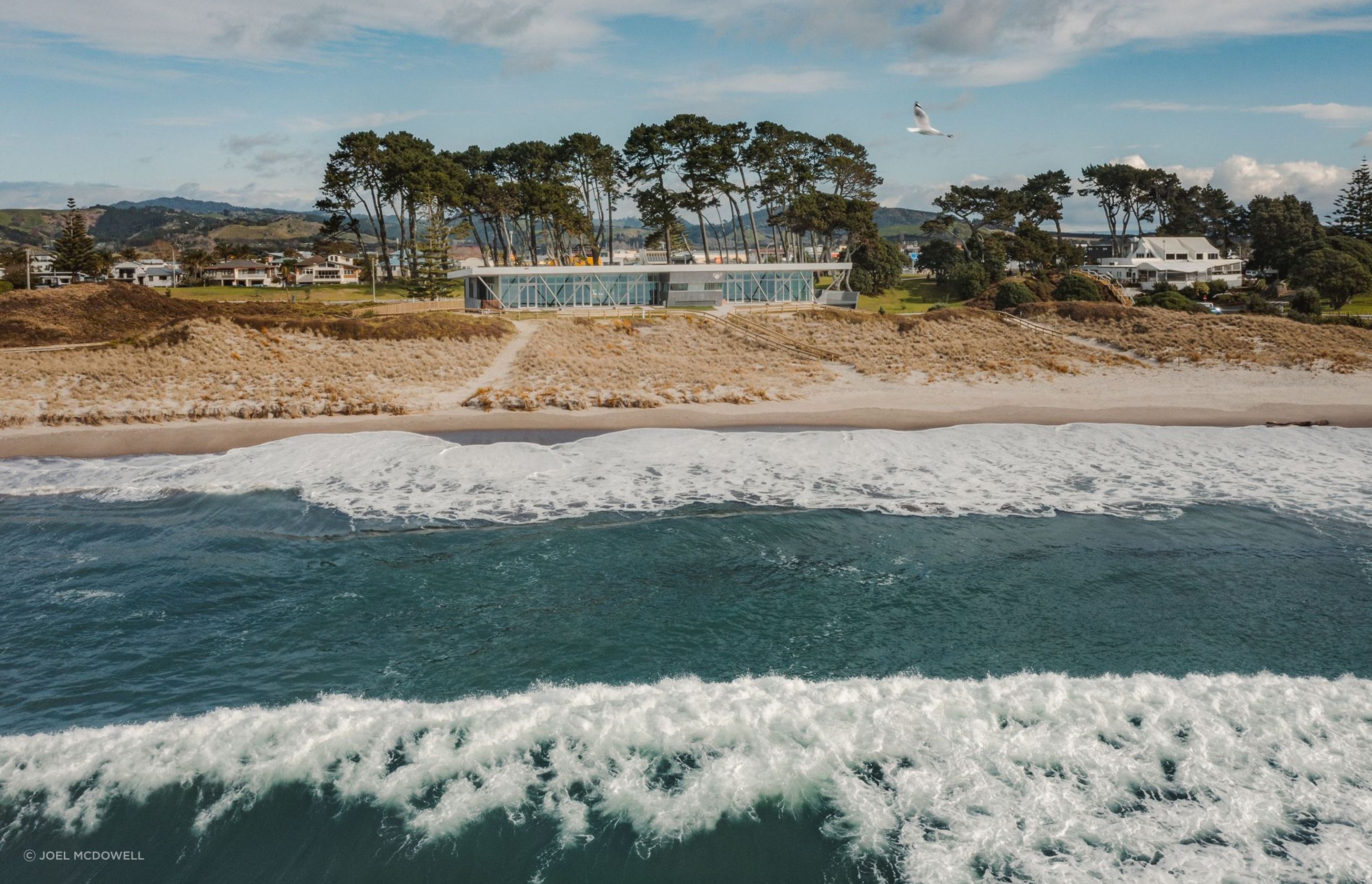 The finished product sits on the dunes of Papamoa Beach, its exterior complementing the surrounding shrubbery and other natural features of the coast.
