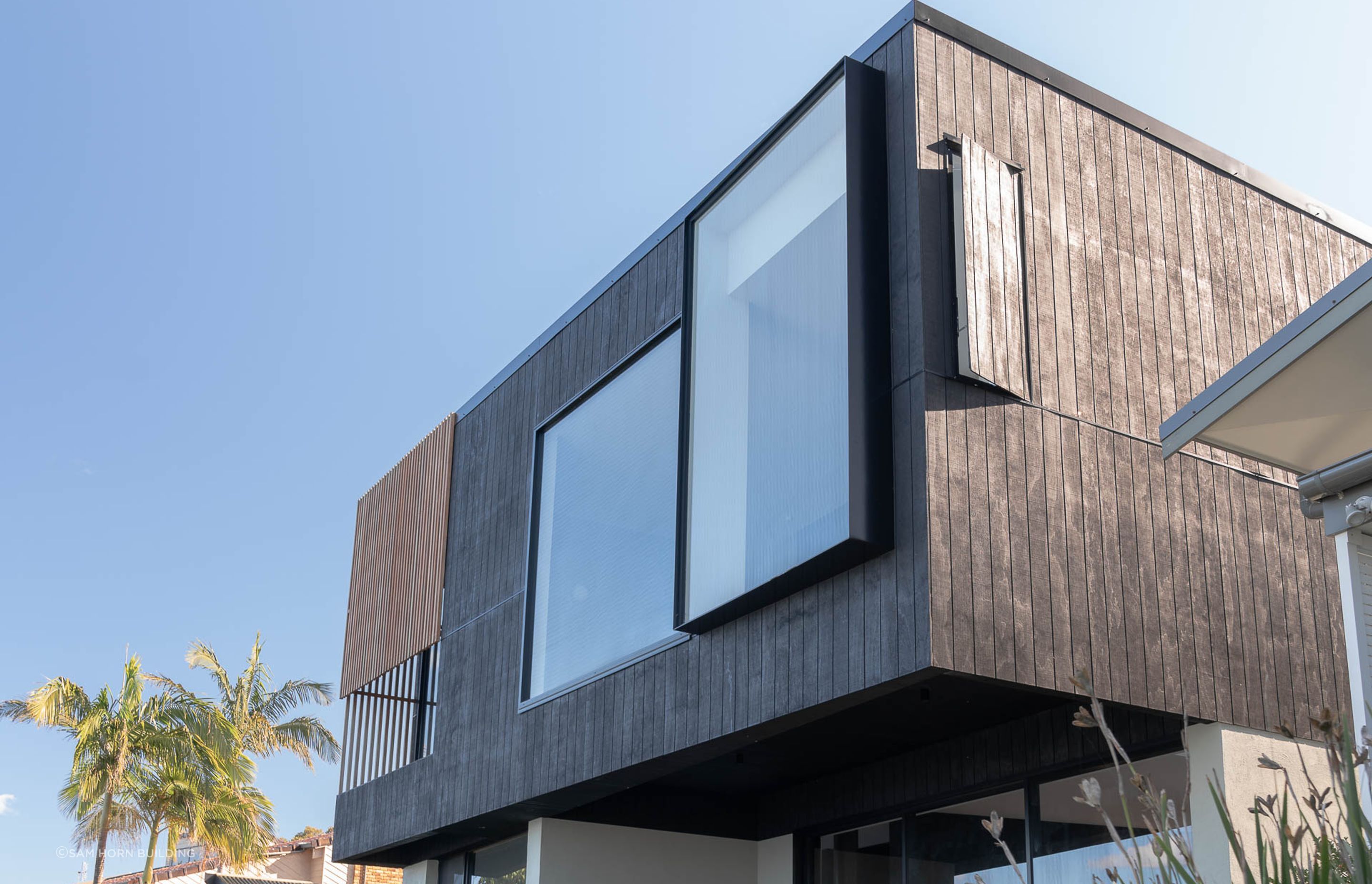 External facade is a captivating combination of charring effect texture paint and blackbutt timber battens