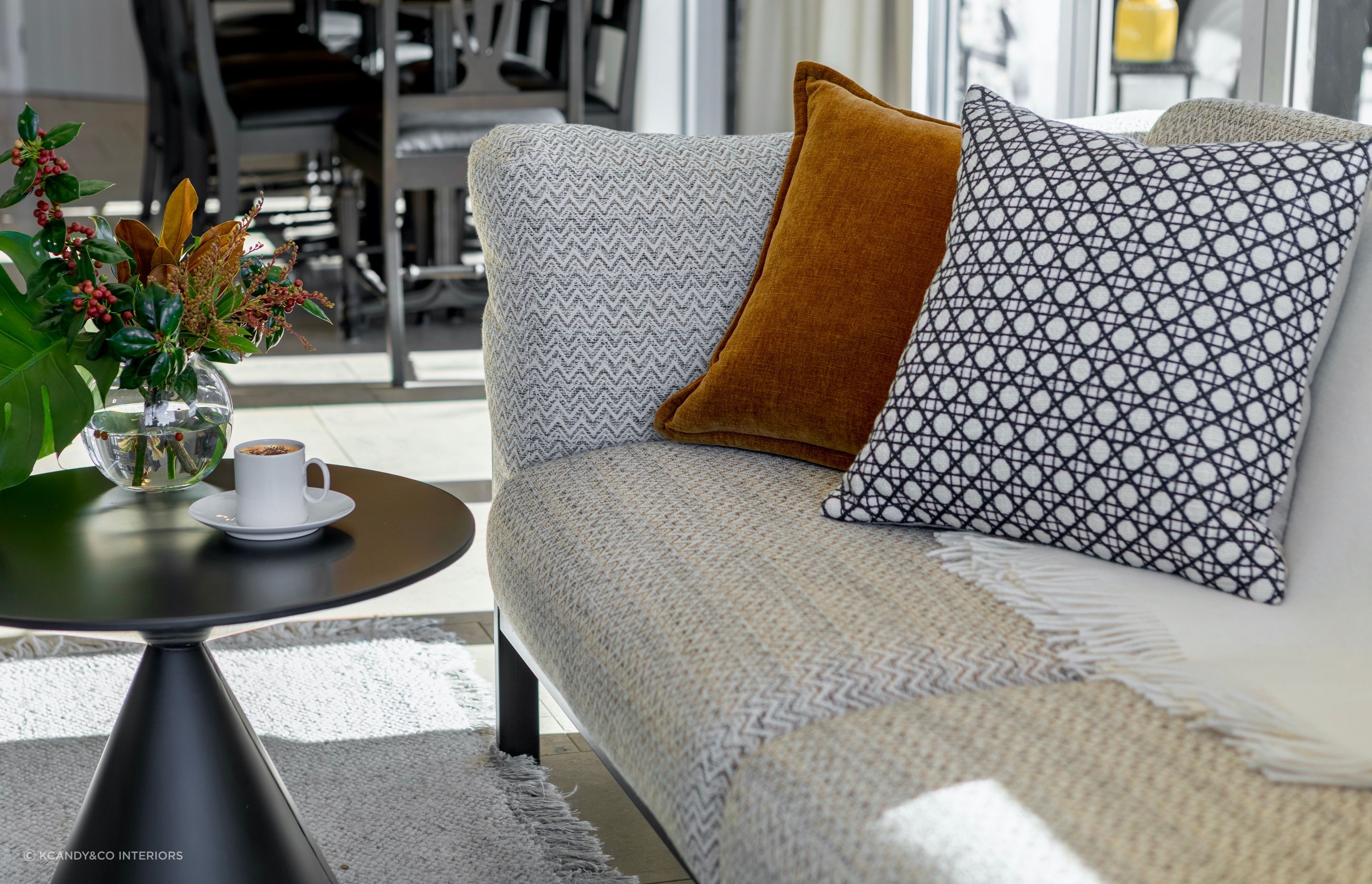 Open plan living room featuring new sofa and soft furnishings. The traditional timber dining chairs were resprayed black to add a contemporary twist.