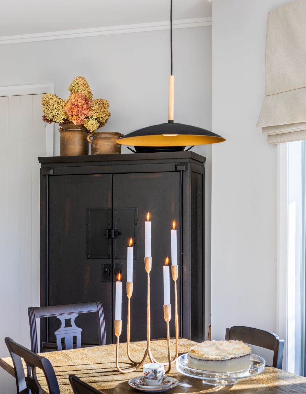 A fresh light white colour palette creates drama and contrast alongside the free standing cabinet and vintage dining chairs