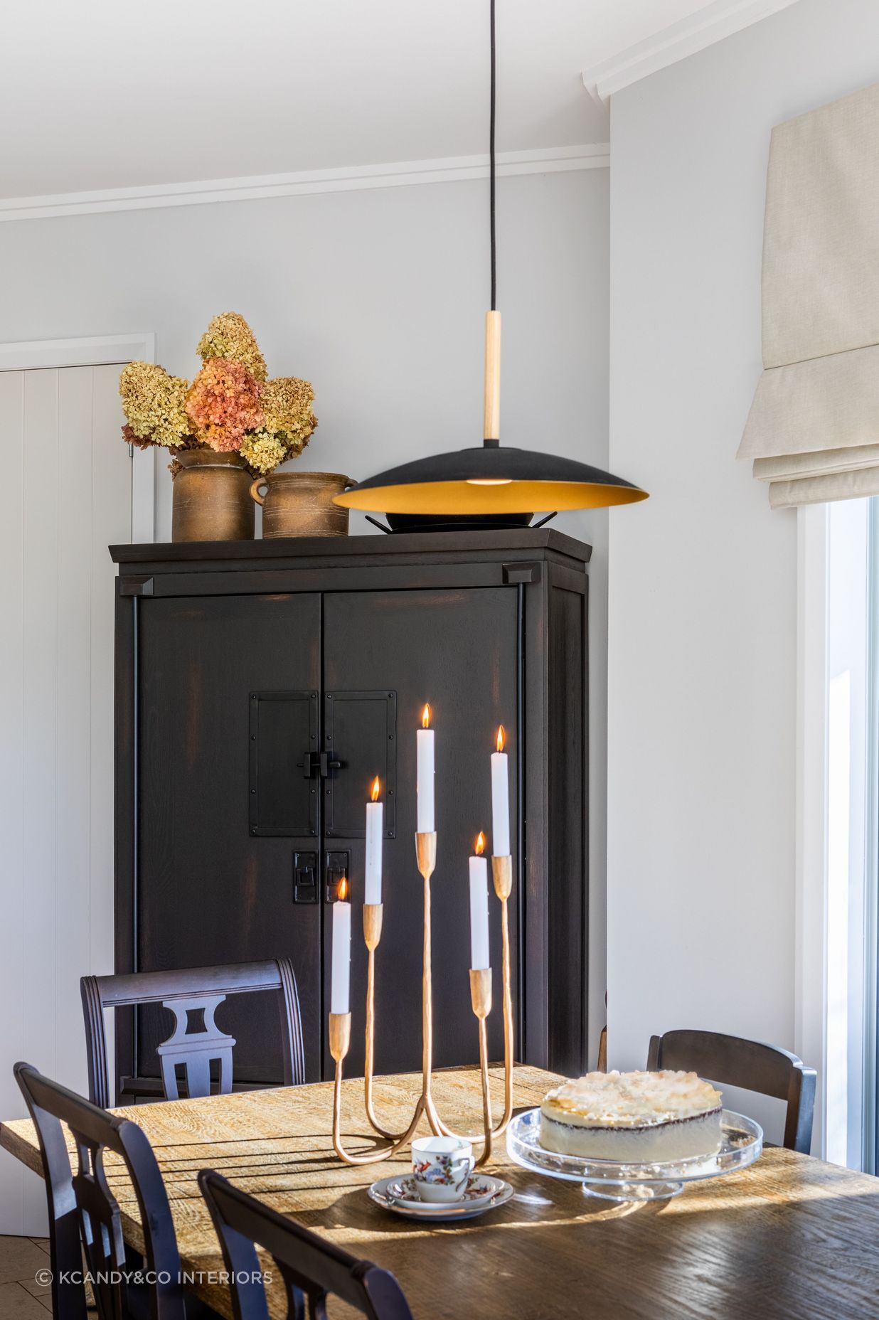 A fresh light white colour palette creates drama and contrast alongside the free standing cabinet and vintage dining chairs