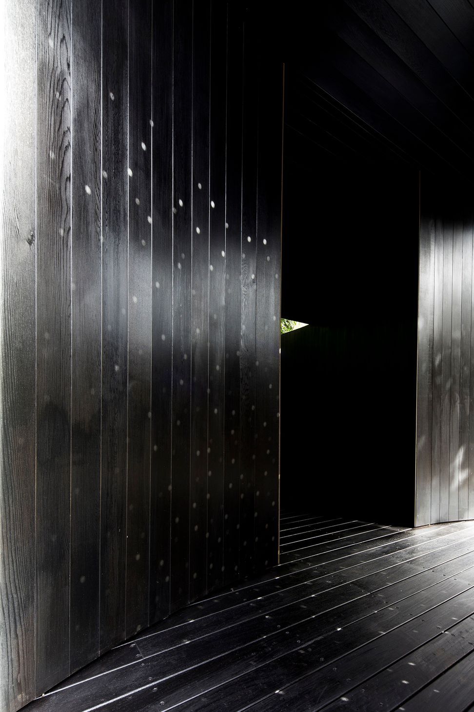 The perforated screen at the entry to the pavilion overlays a lighting pattern onto the solid materiality.
