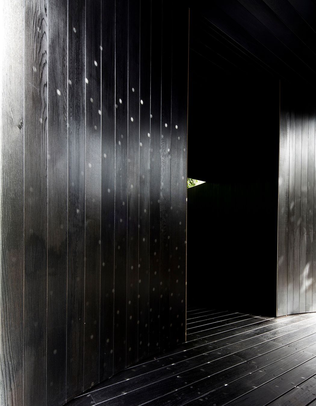 The perforated screen at the entry to the pavilion overlays a lighting pattern onto the solid materiality.