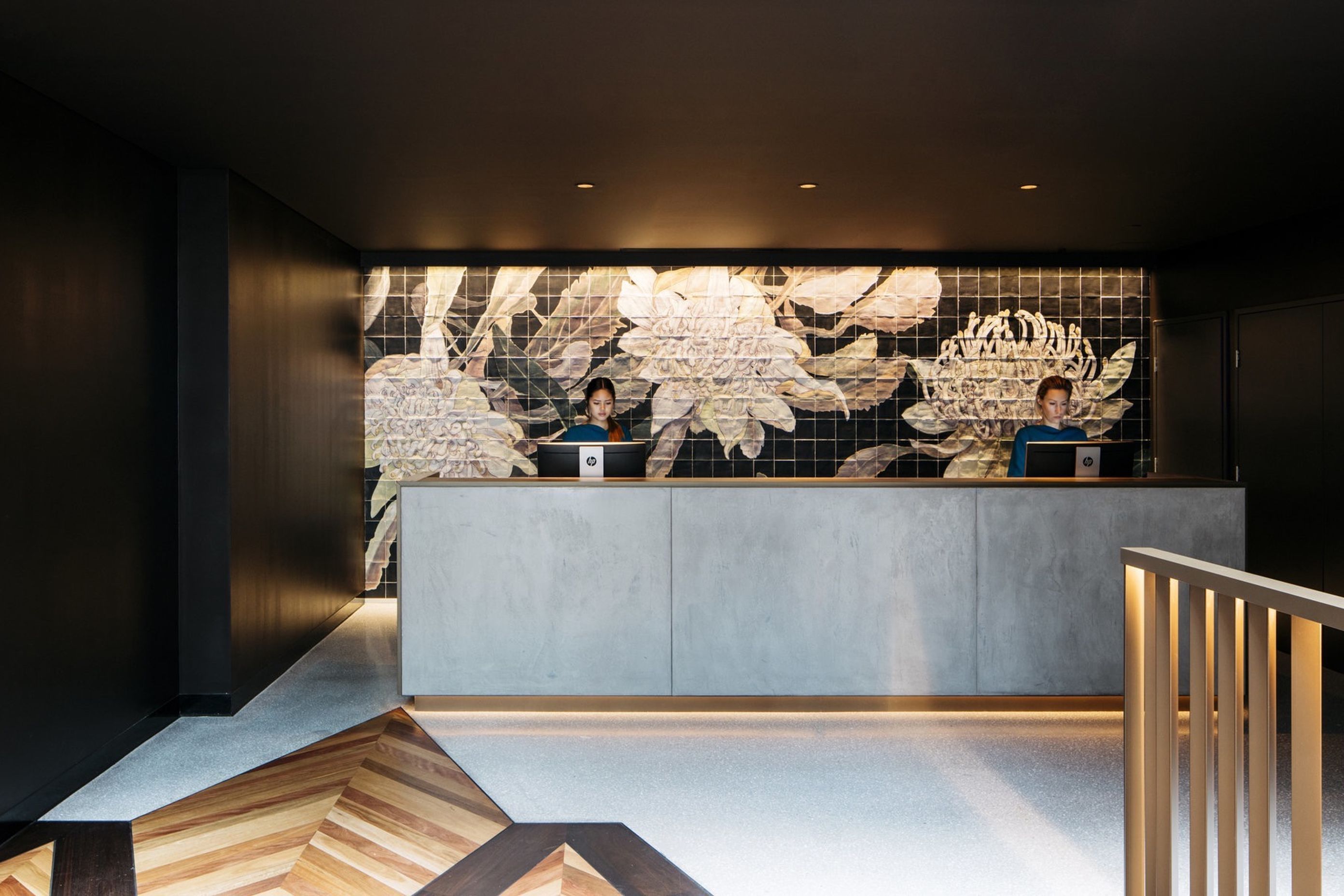 The immersive lobby features charcoal brickwork walls and a graphic timber floor of warm rich tones.
