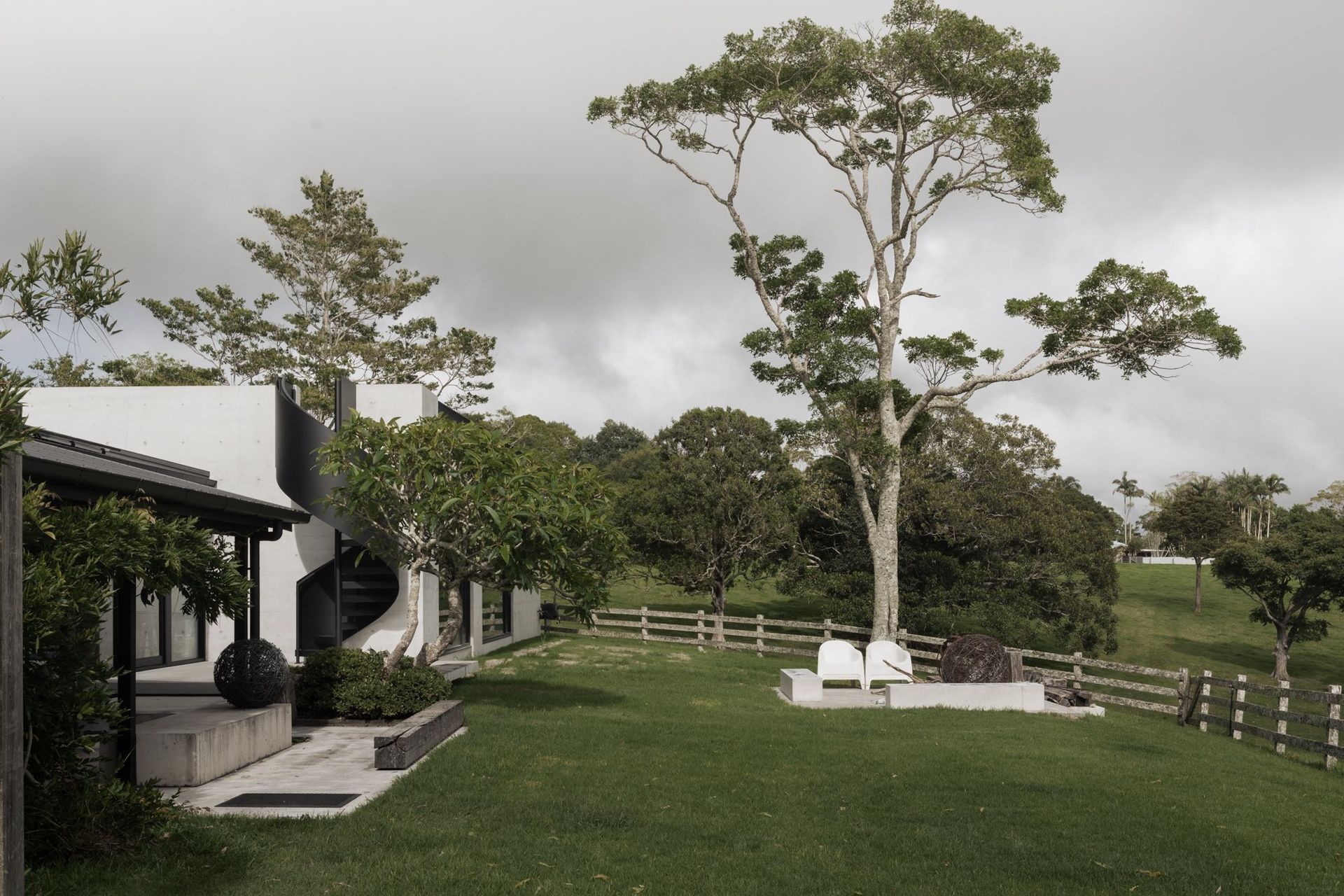 The Farm - Garden. Lawn rolling past the pavilion to a mature gum and timber post fence.